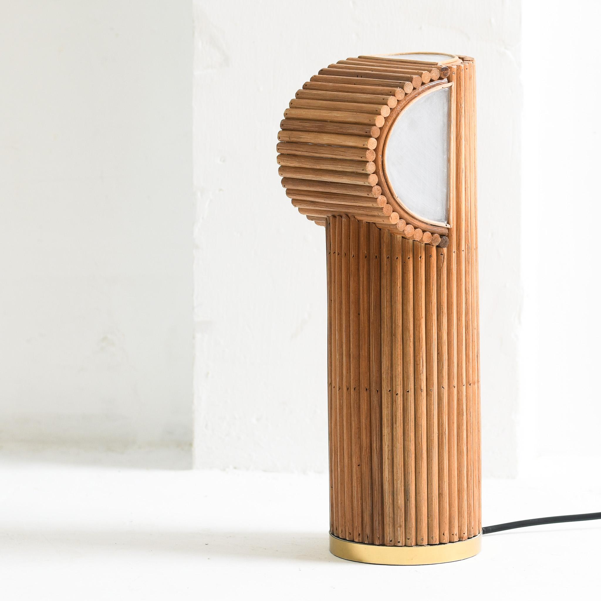 Une élégante lampe de table en rotin de style moderne du milieu du siècle, présentant du rotin organique naturel avec une finition laquée miel, qui dégage de la chaleur et de la texture. La lampe est complétée par un abat-jour en acrylique épuré,
