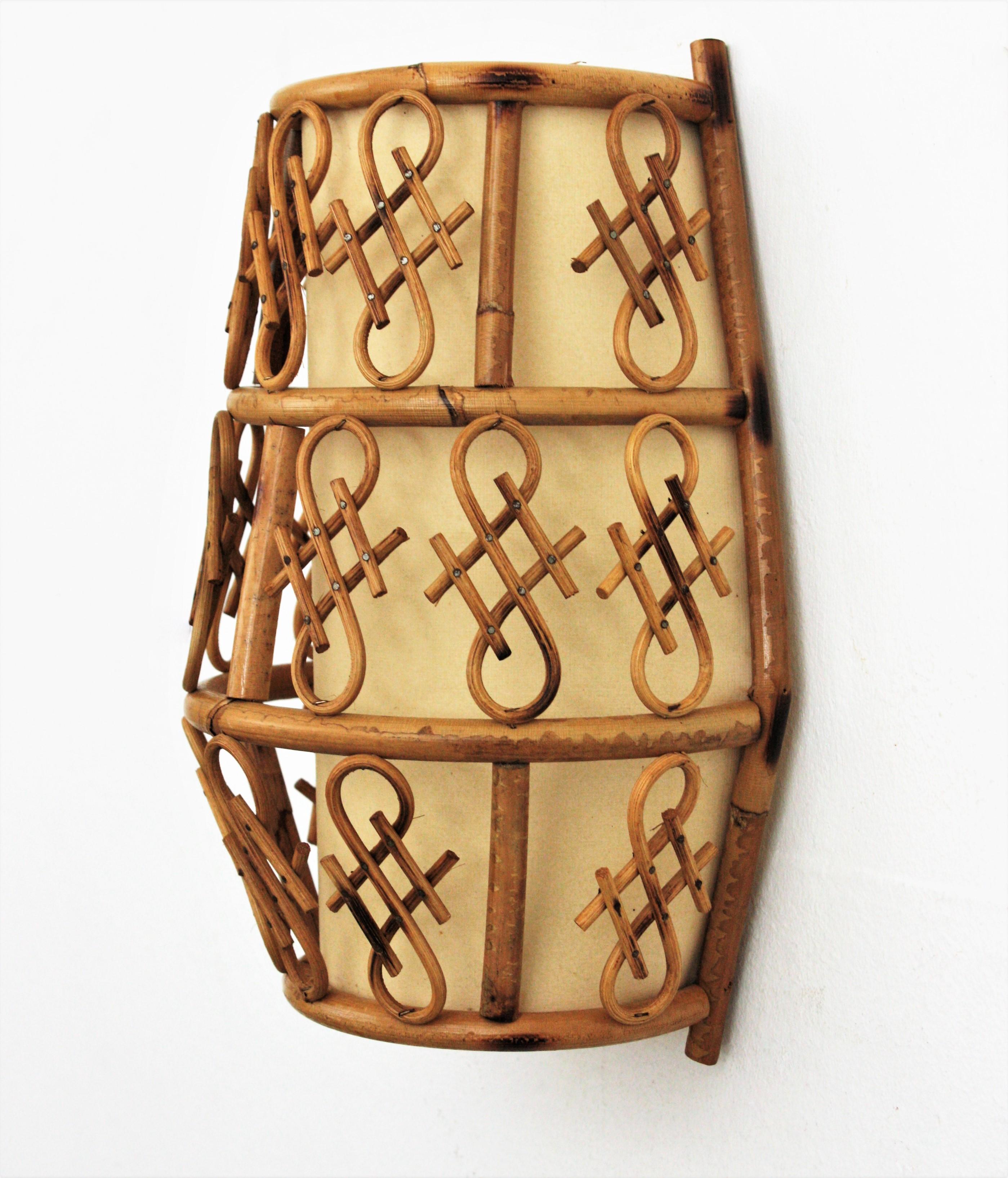 Oriental Inspired Rattan Wall Light
Half cylinder trapezoid bamboo rattan wall light with chinoiserie details, France, 1960s.
This oriental inspired light fixture is made with a rattan structure accented by chinoiserie decorations in rattan.  It has