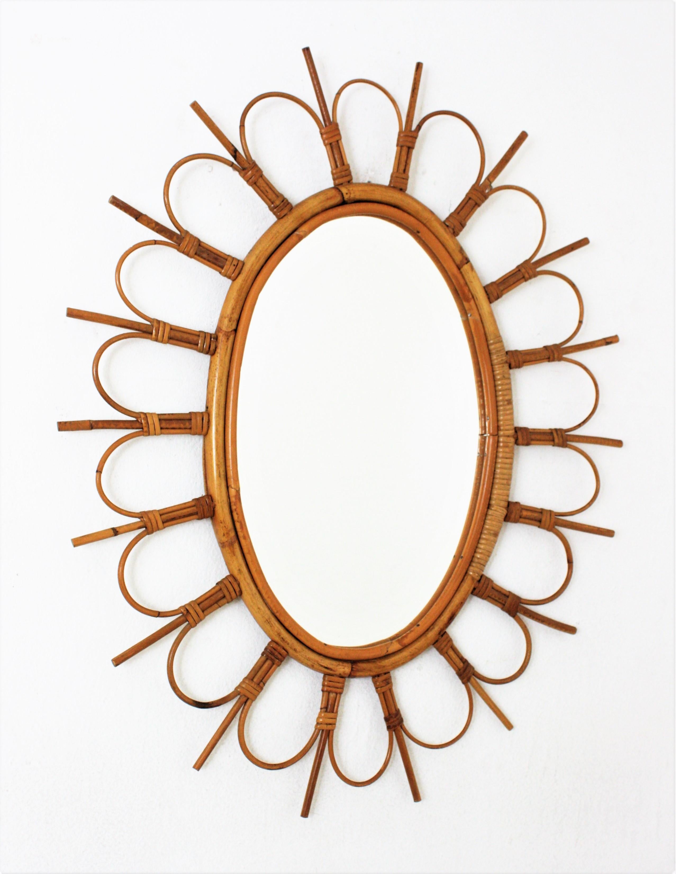 French Riviera rattan bamboo flower sunburst oval mirror. France, 1960s.
This eye-catching rattan wall mirror features an oval bamboo frame surrounded by rattan canes as petals in flower disposition alternating with sticks creating a sunburst
