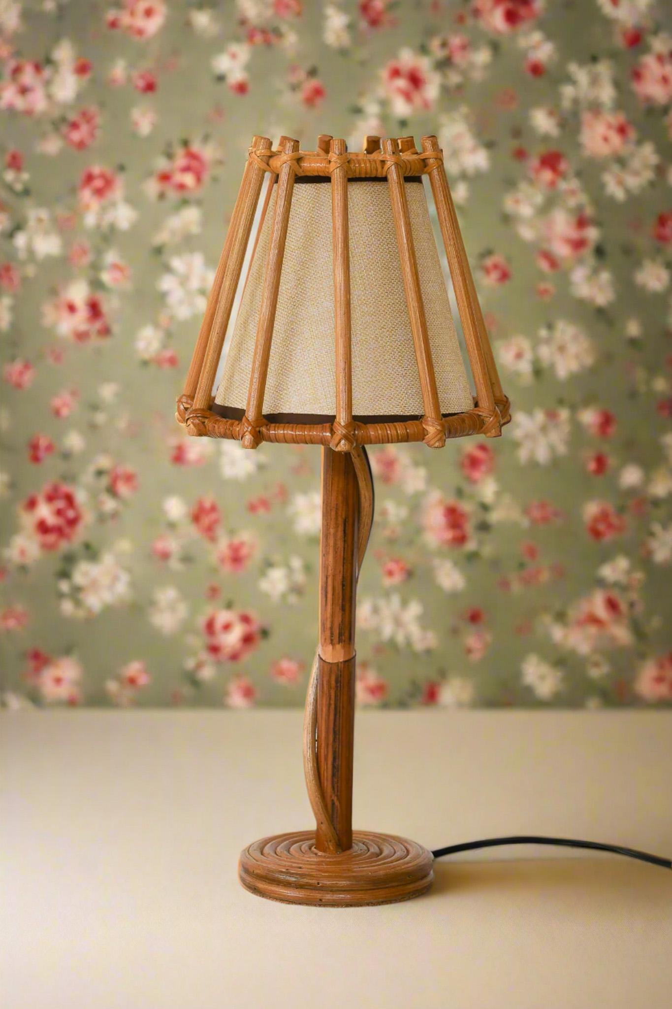 Un'affascinante miscela di eleganza senza tempo e artigianato, questa lampada da tavolo in rattan in stile vintage è un delicato pezzo d'accento per gli amanti dell'arredamento naturale ed ecologico. Realizzata a mano in rattan sostenibile, la sua