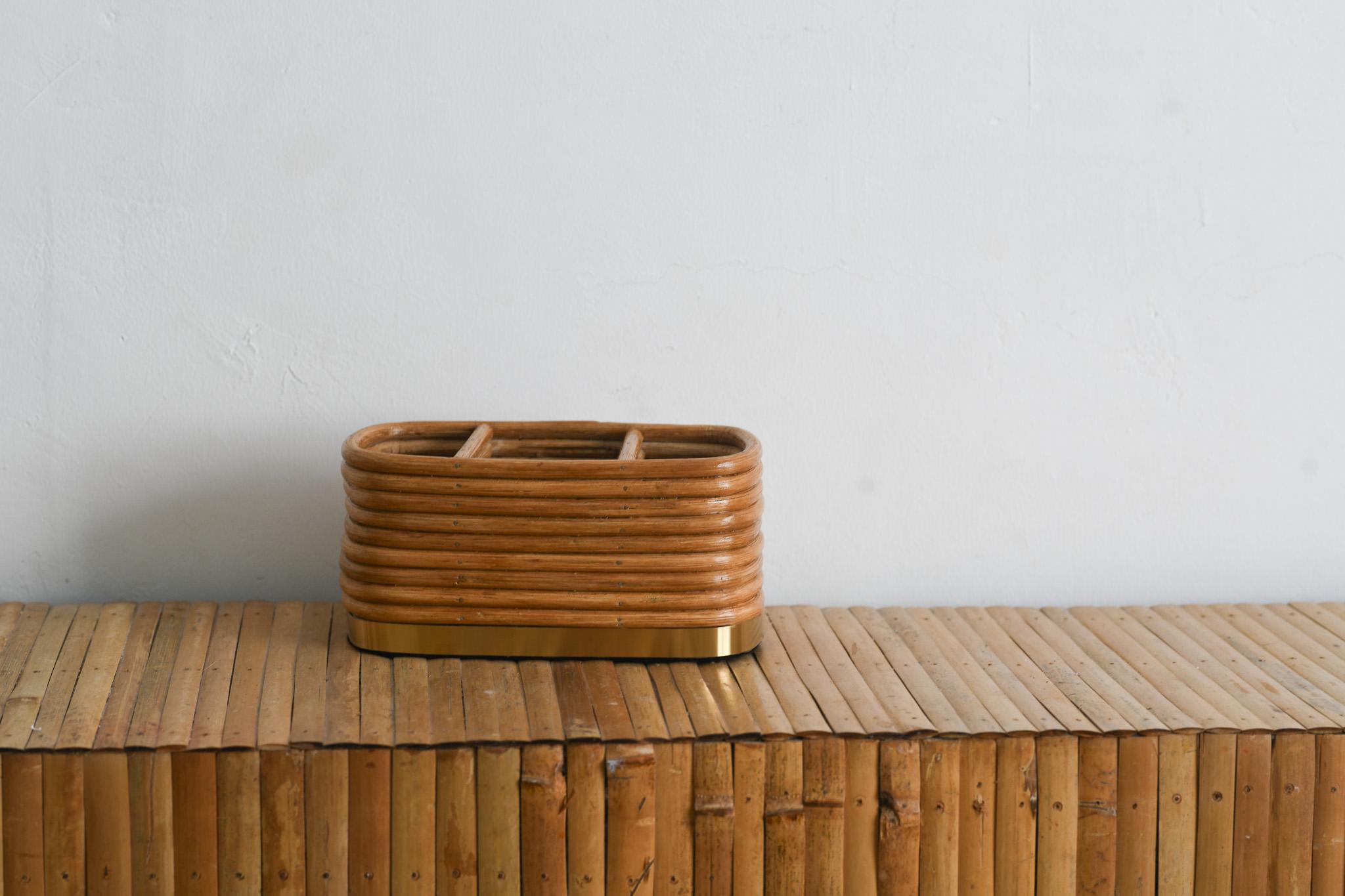 This elegant mid century modern rattan pencil reed desk organizer features a beautiful texture and gold accents. Its three compartments offer practical storage while its rectangular shape with curved edges adds a touch of sophistication to any