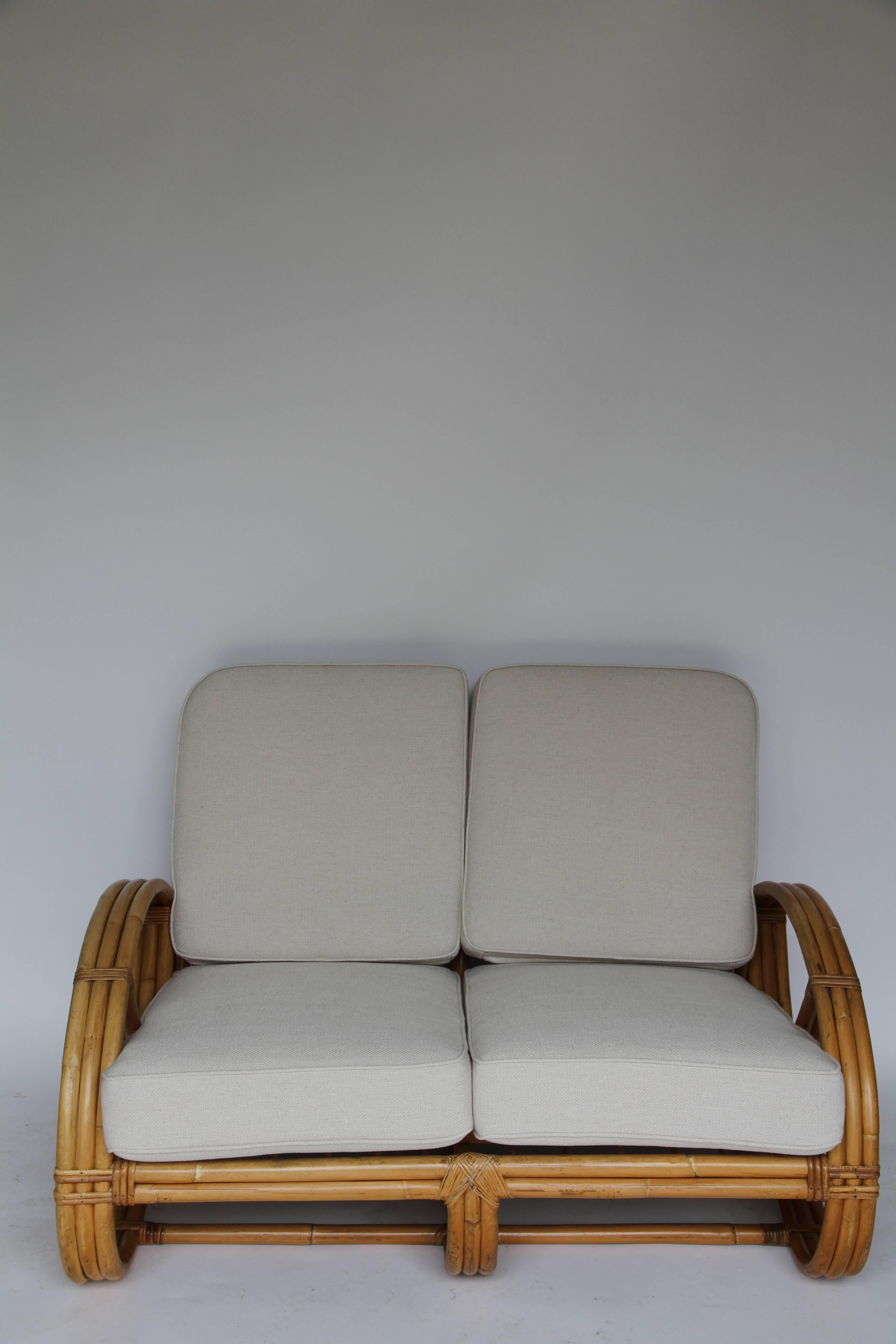 Three-strand round pretzel arm rattan loveseat in the style of Paul Frankl, with custom-made cushions.
 