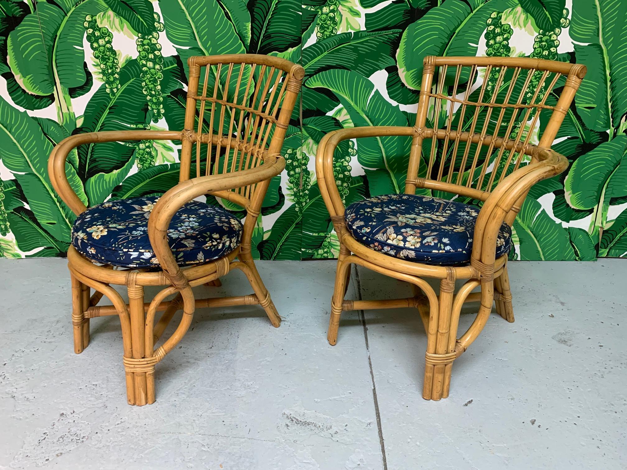 Pair of vintage rattan club chairs similar to the iconic pretzel style made popular by Paul Frankl. Stick backs and floral cushions. Good condition with minor imperfections consistent with age.