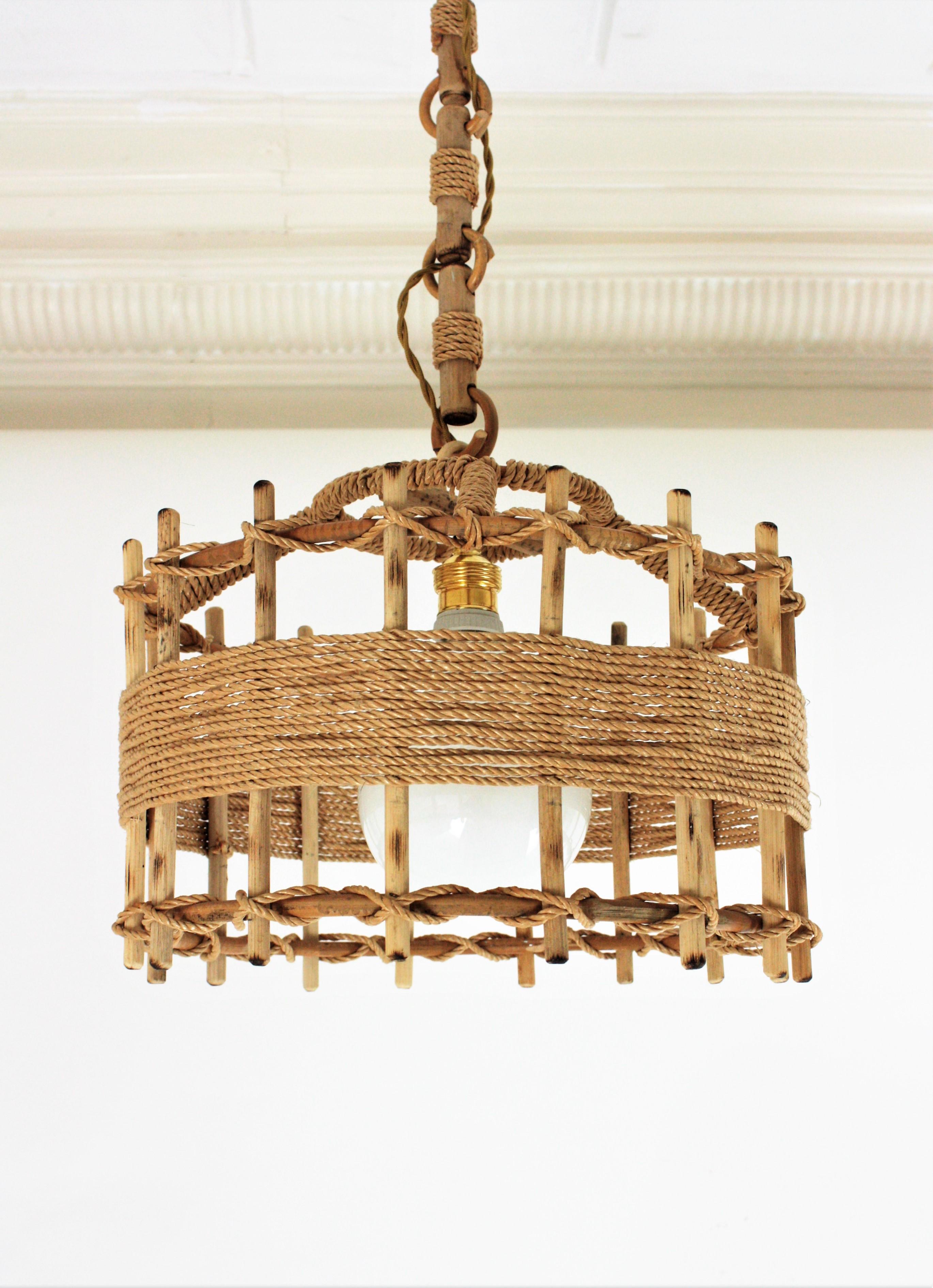 A cool handcrafted rattan drum shaped ceiling suspension lamp in rope and rattan. Spain, 1960s
This large artisan lantern has an eye-catching design featuring a cylindrical structure made of rattan sticks wraped and detailed with jute rope.
 It