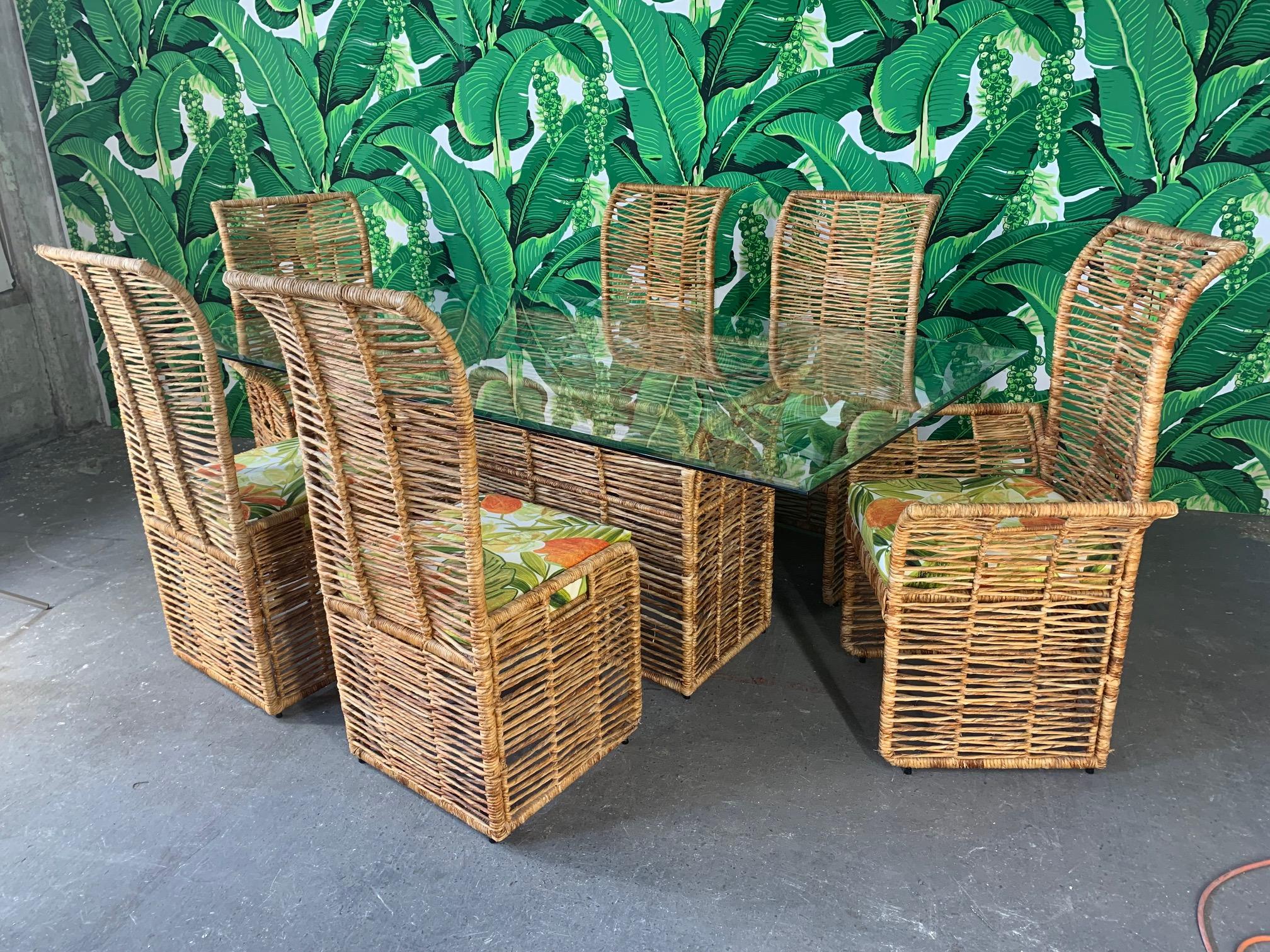 Unique dining set consists of 6 rattan rope wrapped dining chairs upholstered in a tropical palm leaf print and matching pedestal table with glass top. Steel frame construction, heavy and sturdy. Two arm chairs and four side chairs. Very good