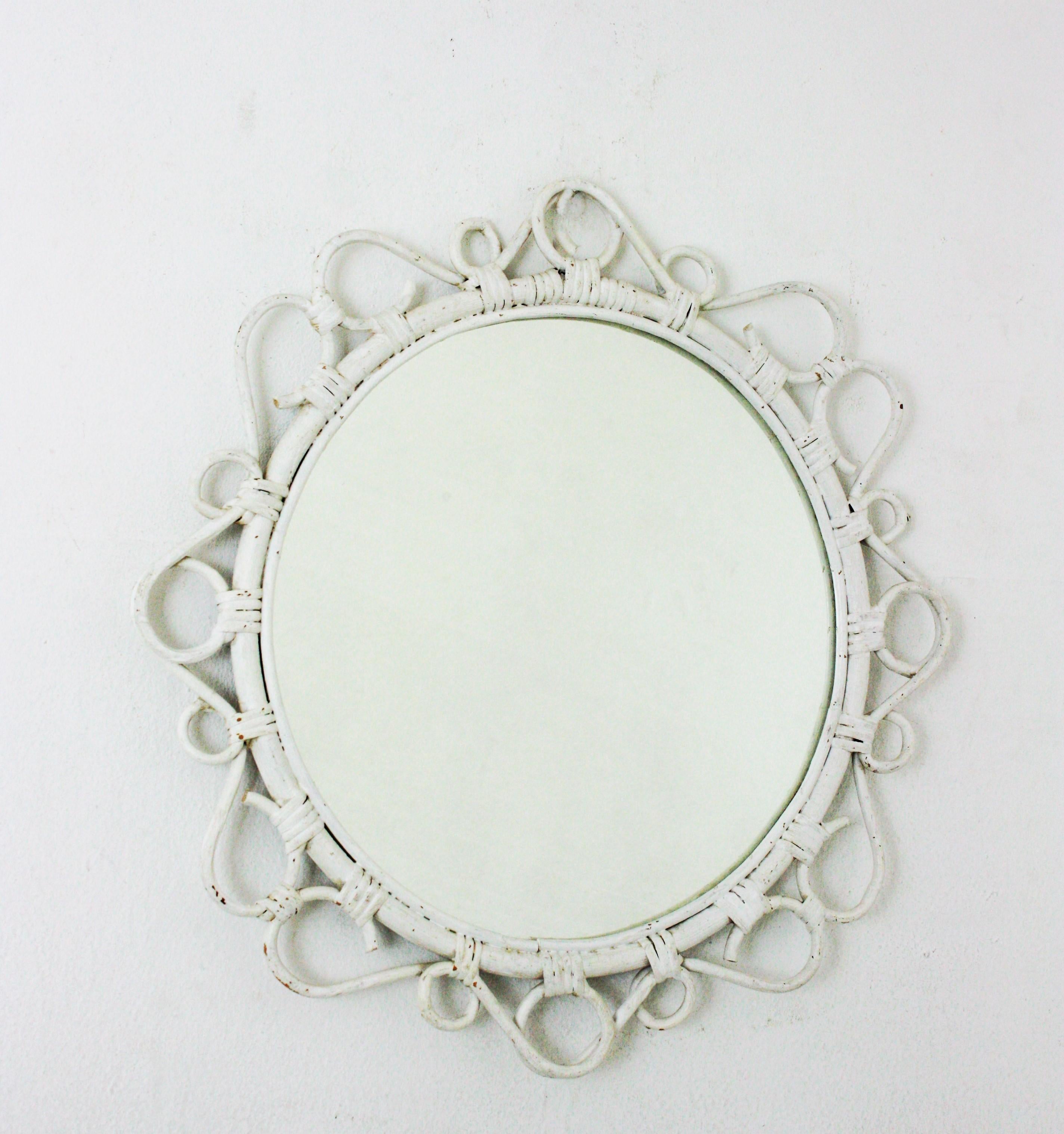 Handcrafted bamboo and rattan mirror patinated in white with scroll detailings surrounding the frame, Spain, 1960s. 
This Mediterranean wall mirror features a circular bamboo frame surrounded by rattan scroll and circle decorations.
Painted in