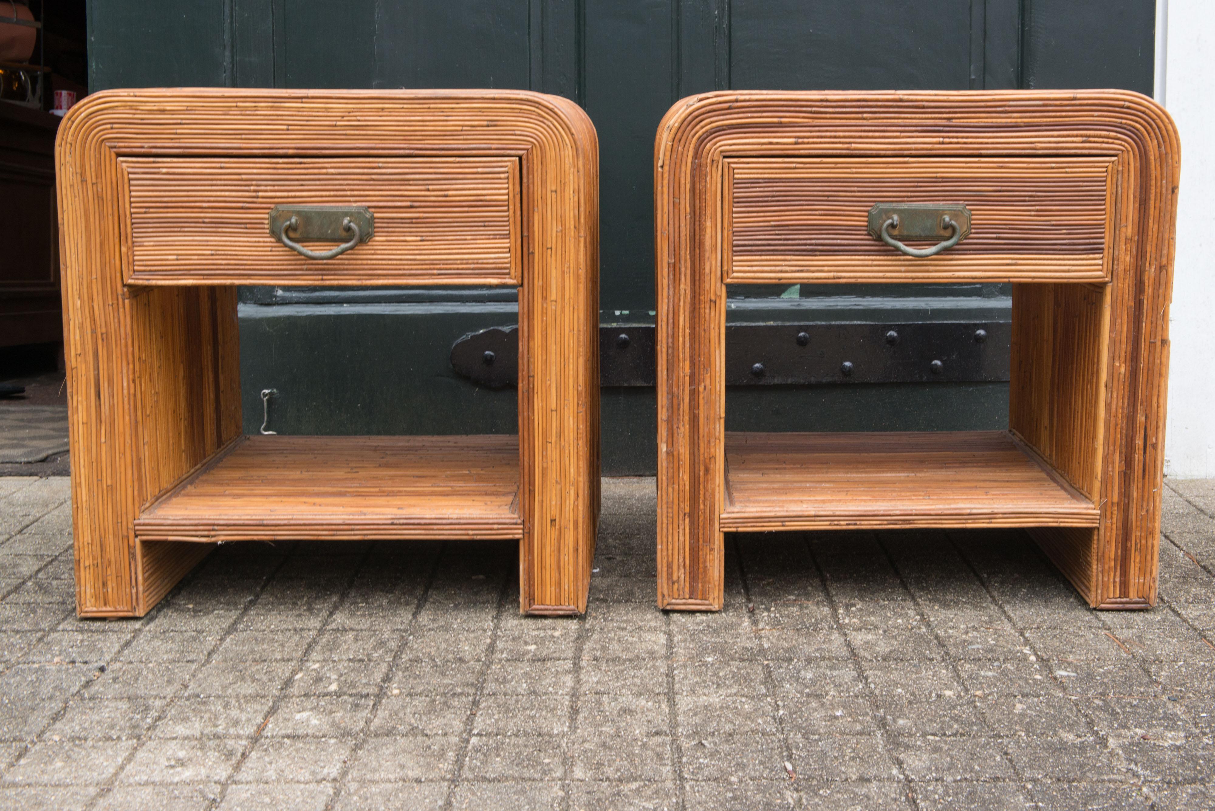 Pair of pencil reed, rattan waterfall style bedside tables or end tables with single drawer and shelf. Back of each table is finished. Timeless and good looking.