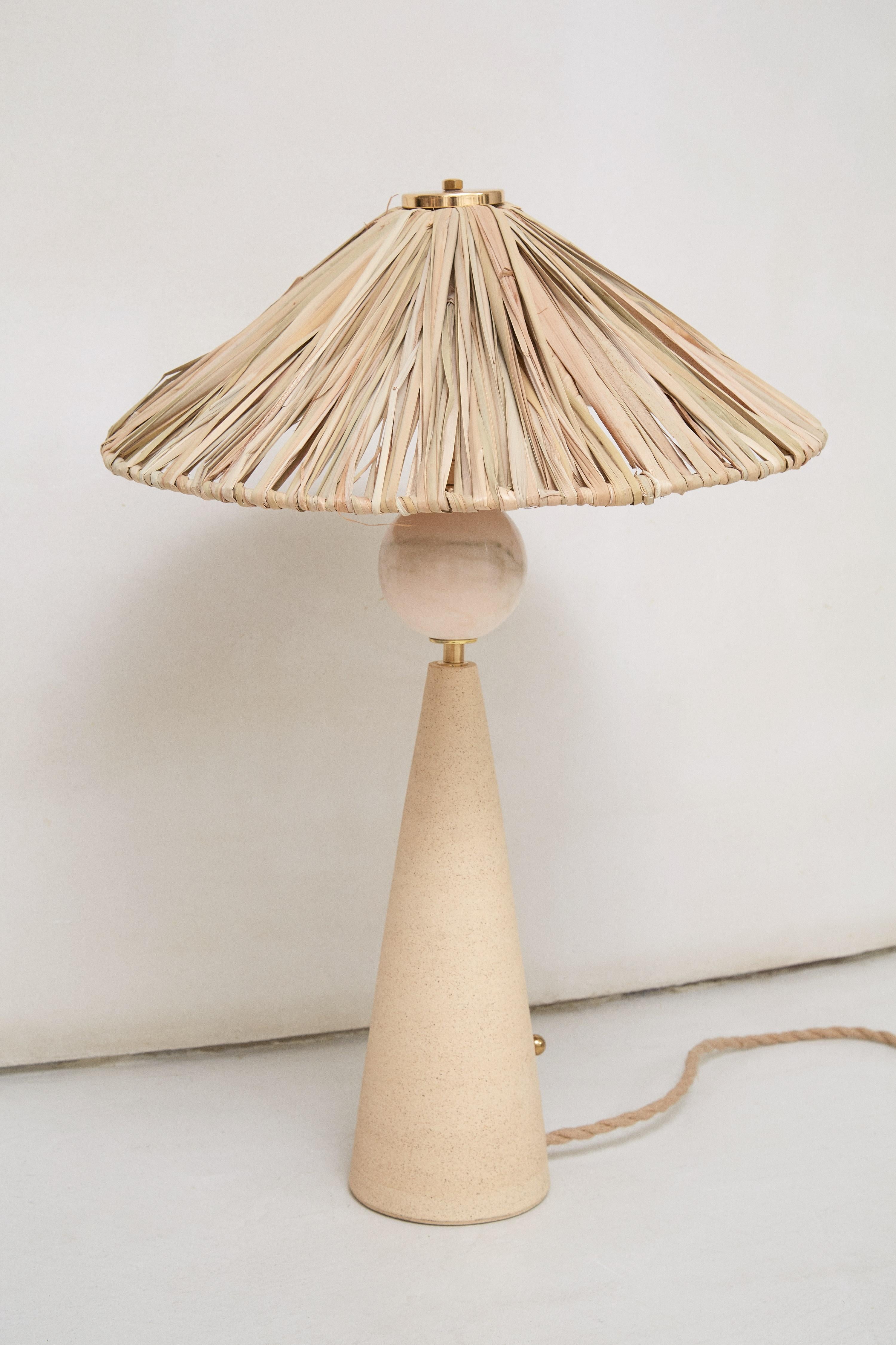 Rattan Table Lamp by Patricia Bustos de la Torre
Dimensions: D 52 x W 52 x H 71 cm.
Materials: Rattan, pink Portuguese marble and brass.

This table lamp immediately transports us to a mediterranean fantasy with its handmade rattan hat. Below this