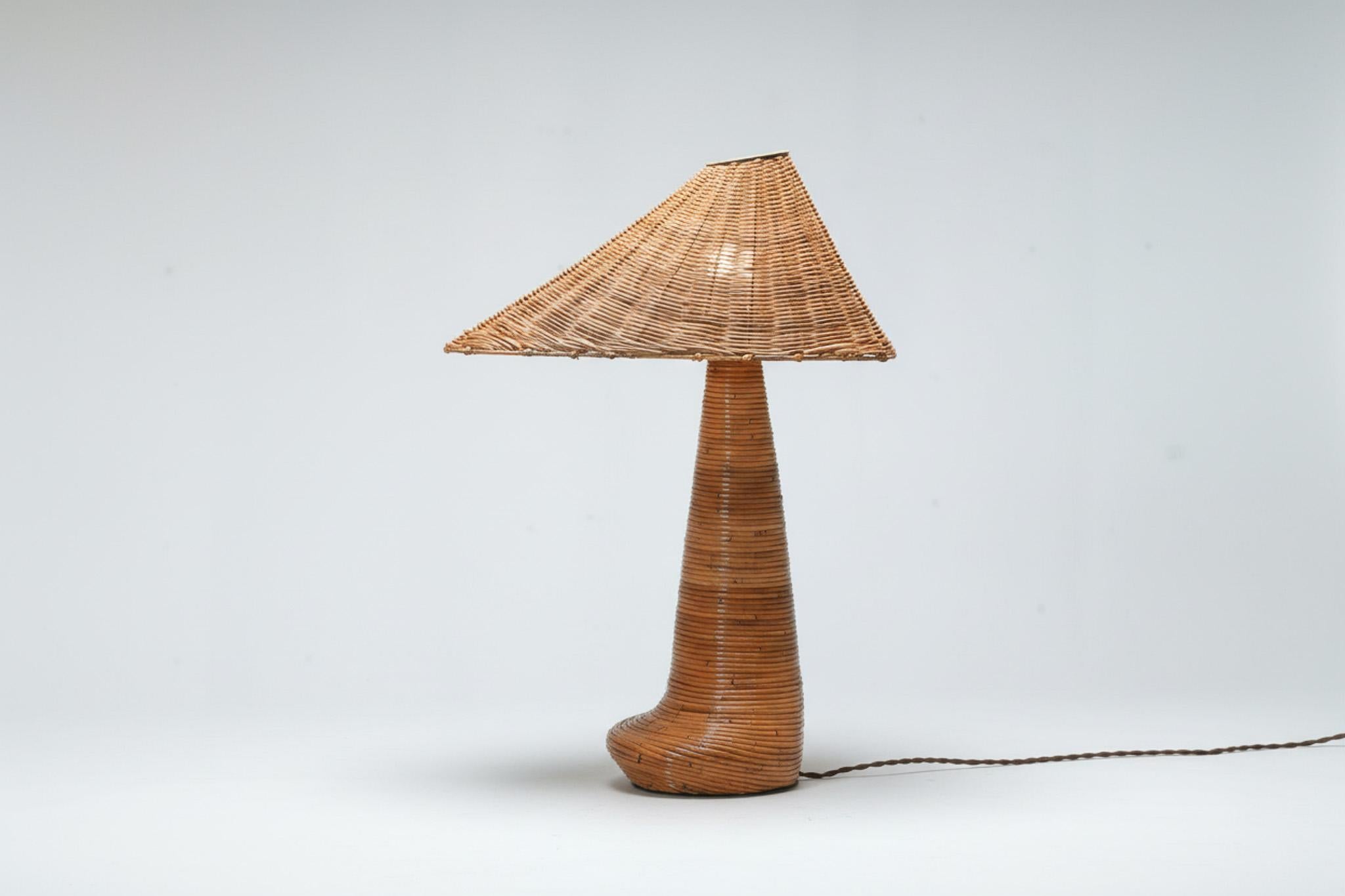 La lampada da tavolo Chloe Rattan combina un'esperta maestria artigianale e un design distintivo, caratterizzato da una forma unica con un paralume in vimini intrecciato a mano e una robusta base in canna. Le sue texture naturali aggiungono calore e