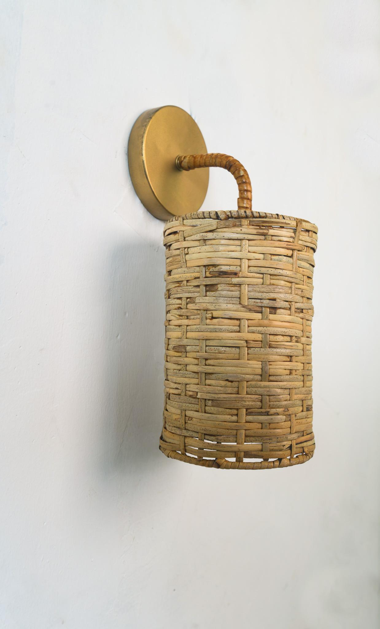 Mid- century modern wall mounted lamp with a rattan shade sculptured piece perfectly suited for the bedroom shade with a subtle light diffuser shade organic rattan golden metal lamp frame with e27. Dimensions 12W-15D-28L. cm