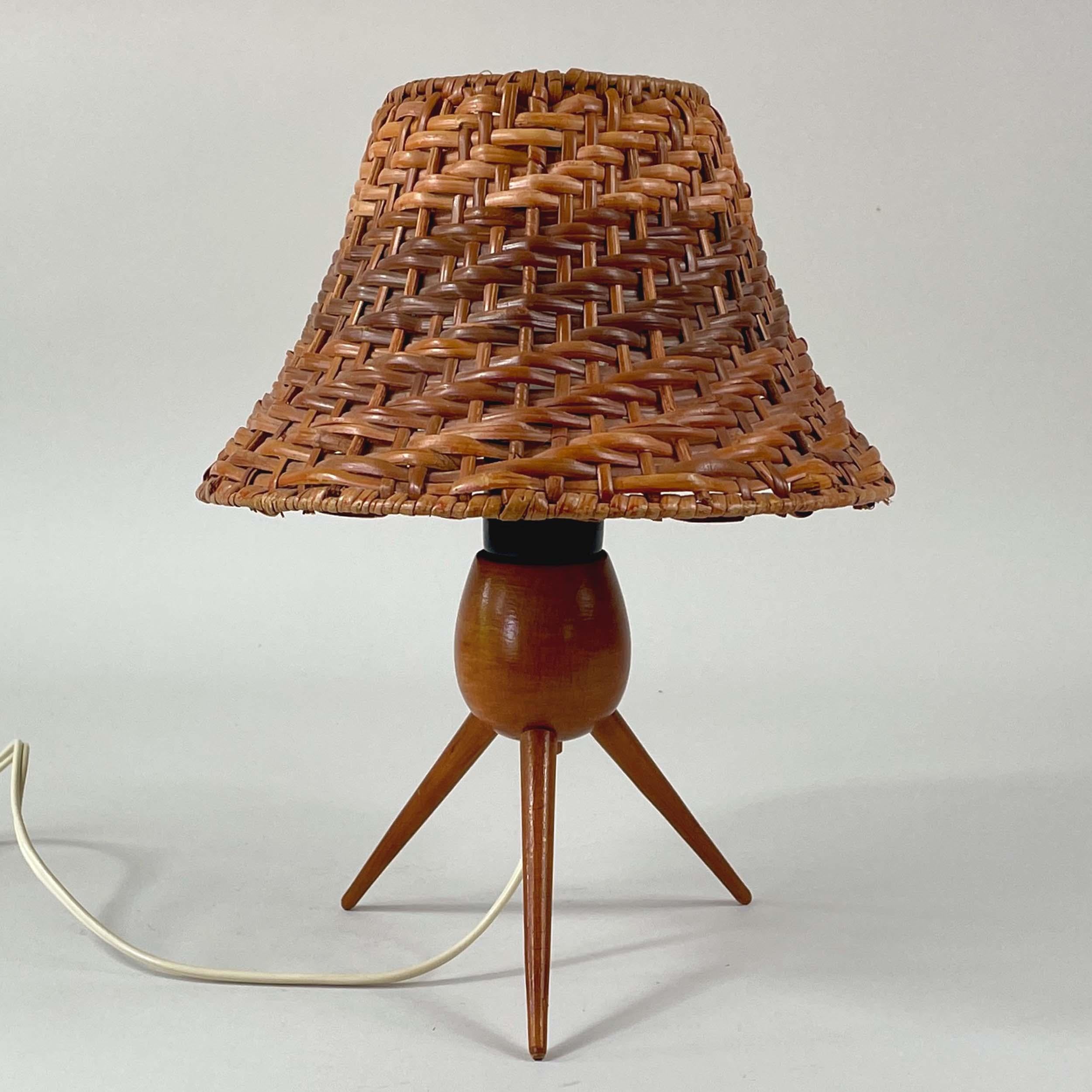 This unusual rattan or wicker table lamp was designed and manufactured in Austria in the 1950s. It features a minimalist birch tripod base with a clip-on rattan lampshade. The lampshade can be moved in different directions.

Good original condition