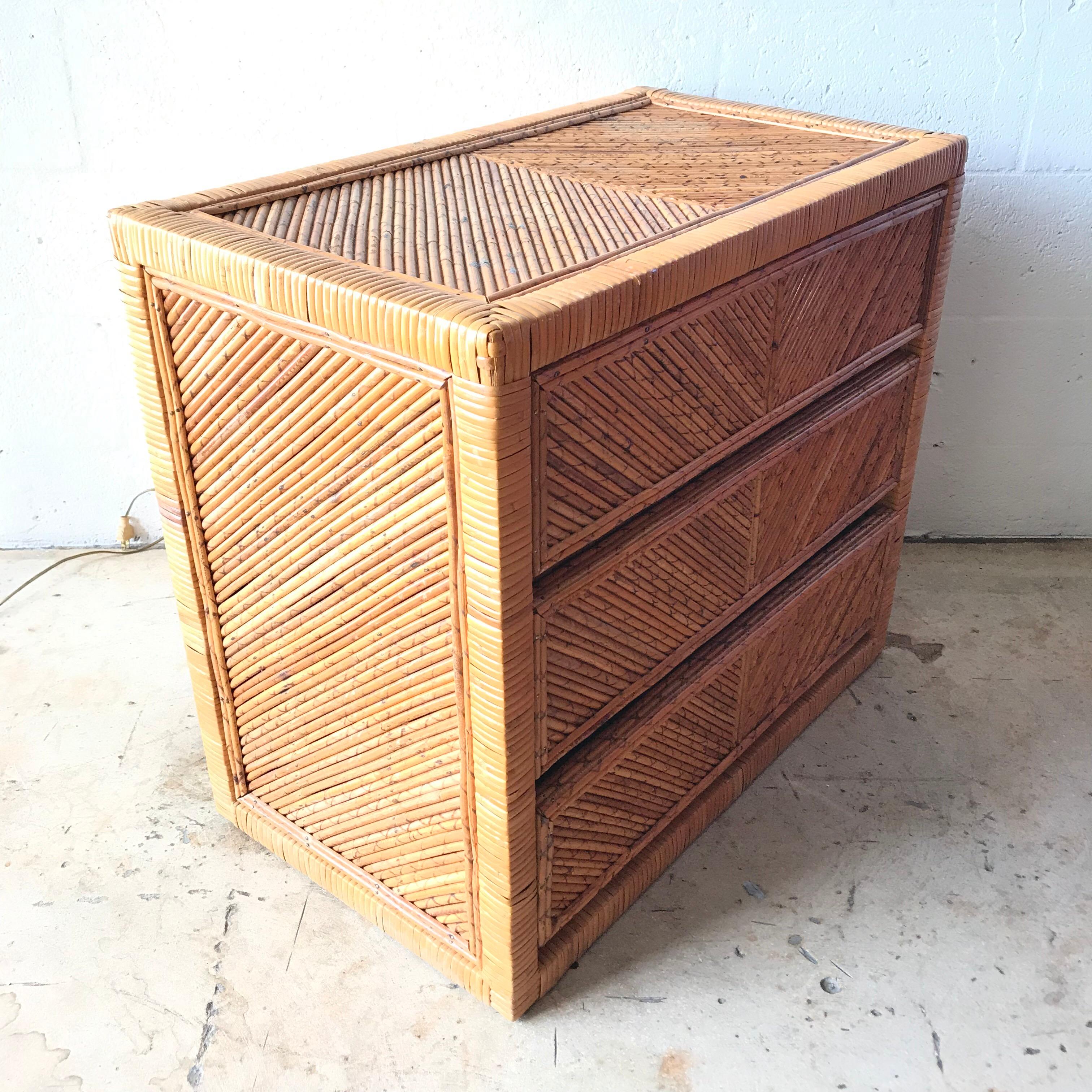 Three-drawer dresser or chest of drawers or commode rendered in wicker bamboo rattan split reed, finished on all sides.