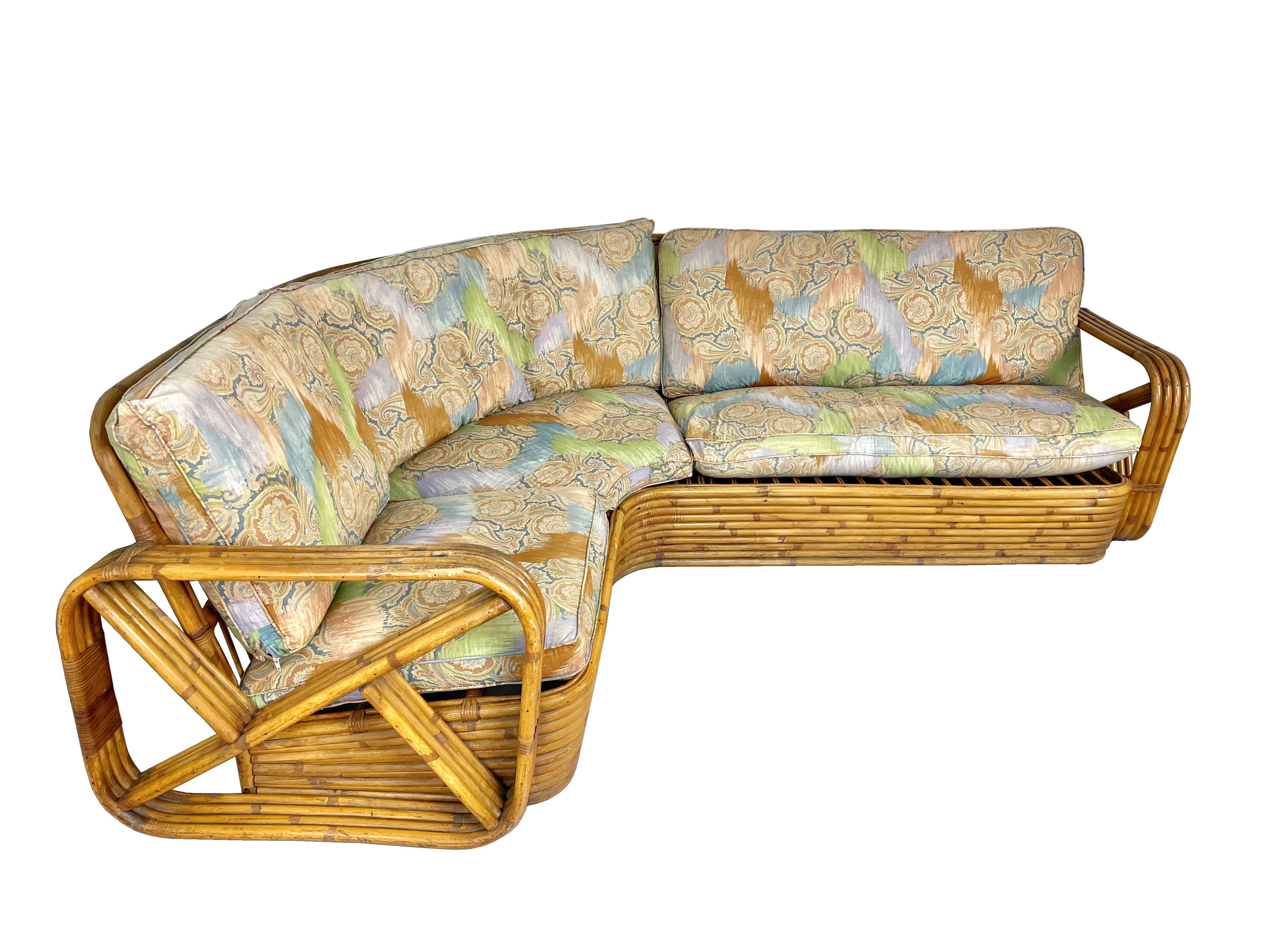 Brezel-Ecksofa aus Rattan, entworfen nach dem Vorbild von Paul Frankl. Dieses einzigartige Sofa besteht aus einem gebogenen Rattansockel mit viersträngigen, quadratischen Brezelarmen und ist ein solides, gebogenes Rattanstück. 

Die Kissen können