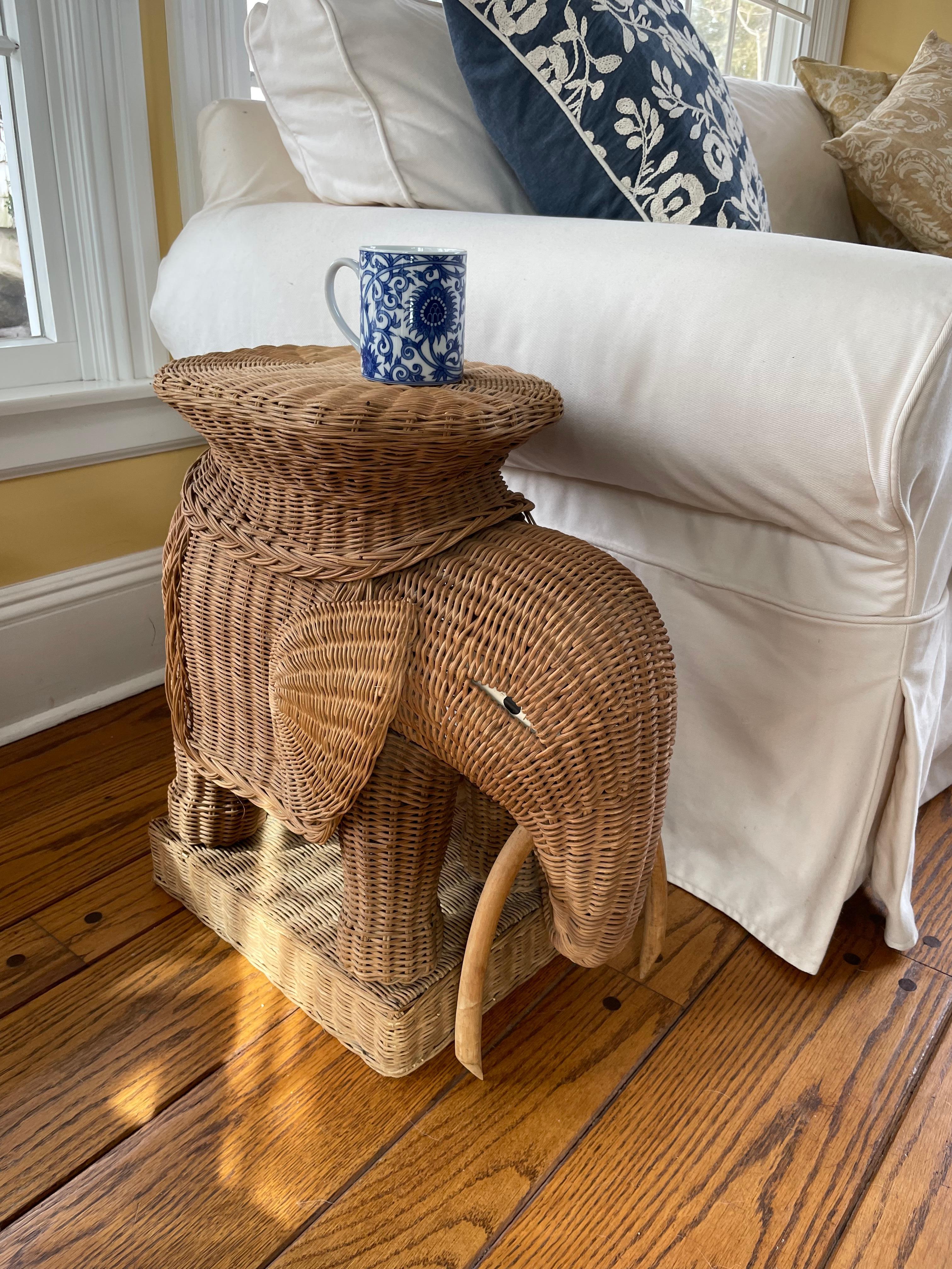 Wicker rattan elephant. Charming vintage drinks stands/side table of in elephant form with flat saddle for drinks or your favorite book; with painted eyes and rattan tusk. France, circa 1960. 
Dimensions: 20