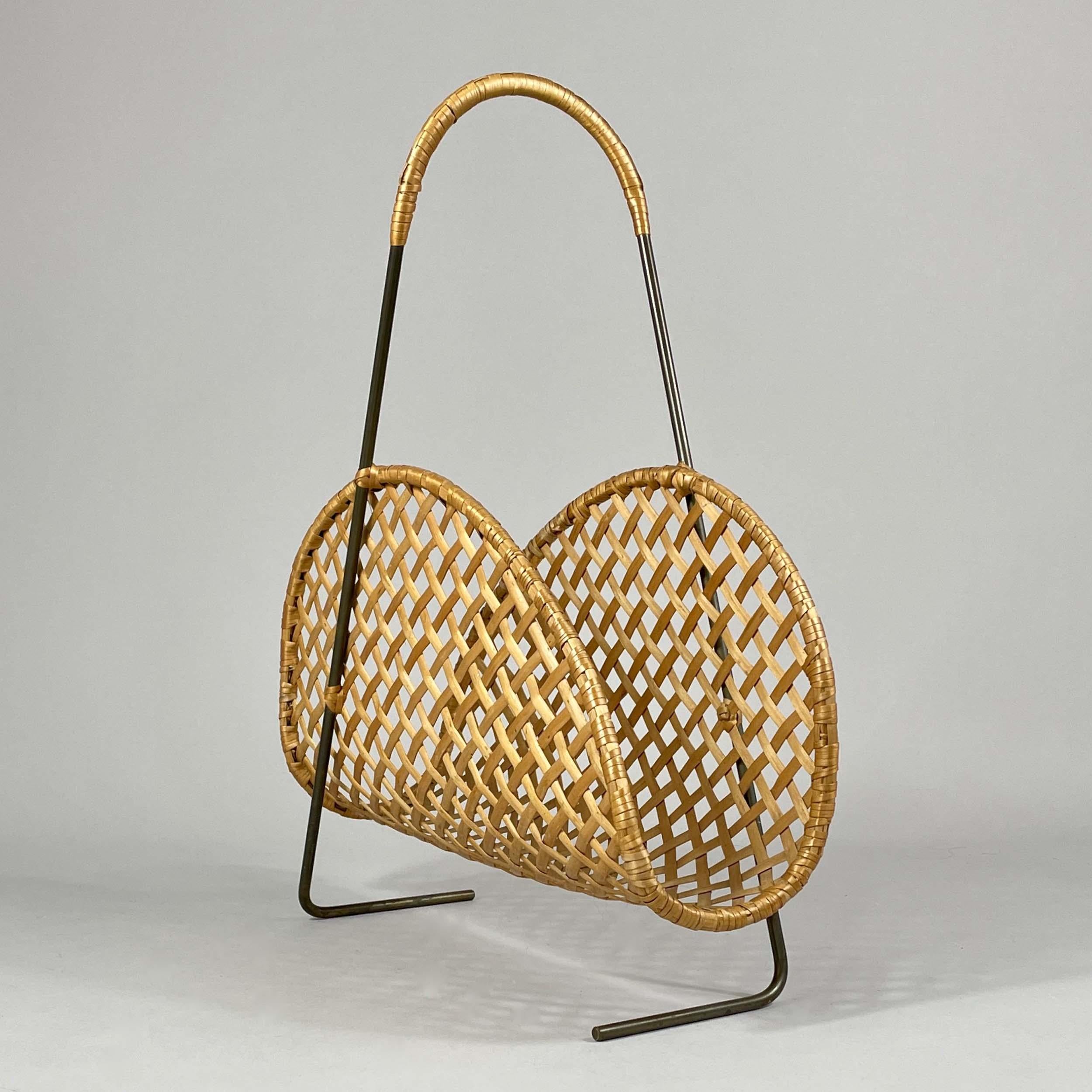 Questo elegante portariviste è stato progettato e prodotto in Austria negli anni Cinquanta. 

Presenta un corpo in rattan intrecciato con un motivo a croce aperto e un sottile telaio in ottone brunito con i tipici piedi a 
