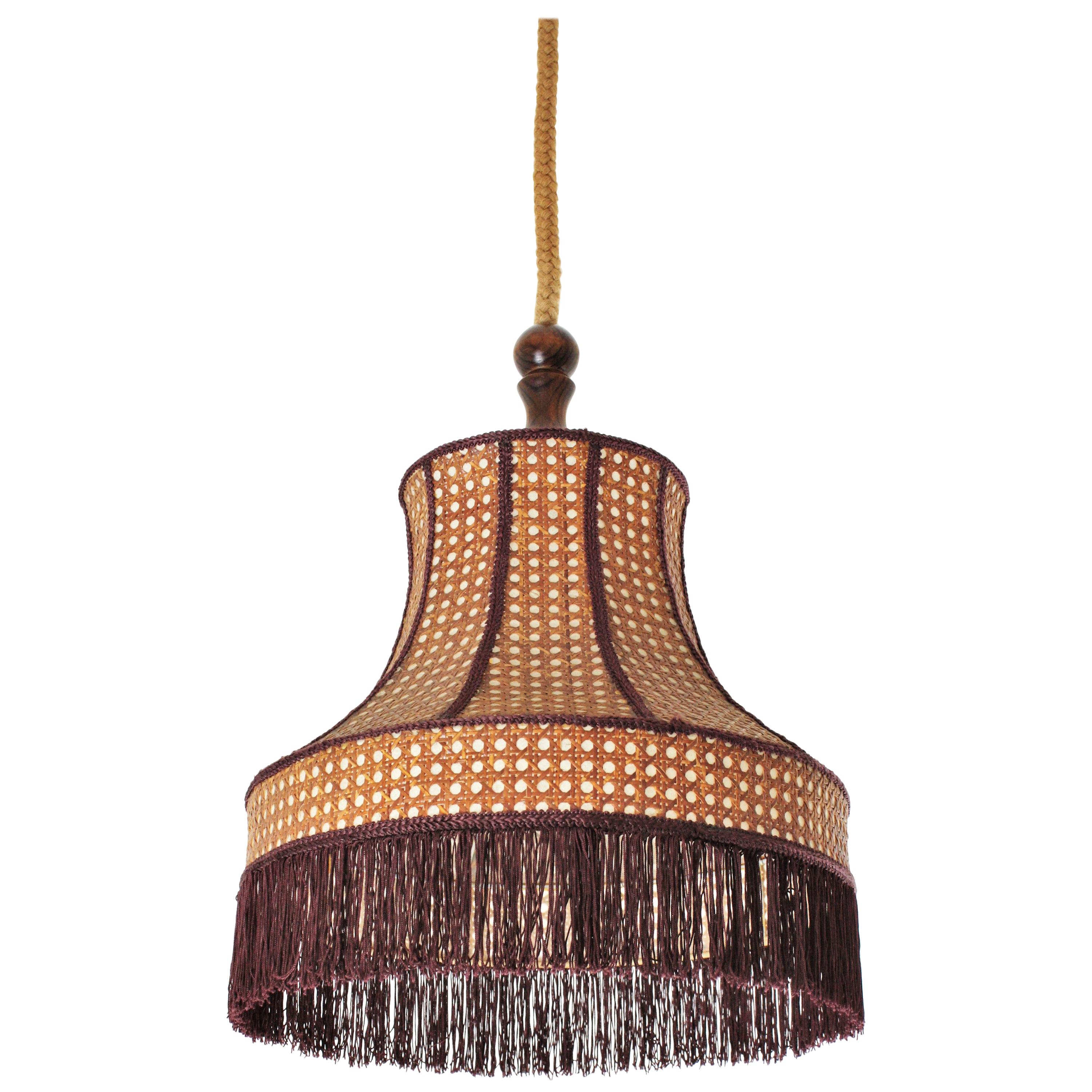 Wicker wire pagoda shaped pendant or chandelier with wood, rope and fringe details, France, 1960s.
This midcentury pendant lamp features a wicker wire pagoda fringe lampshade. It hangs from its original rope and wooden canopy.
The pagoda wicker