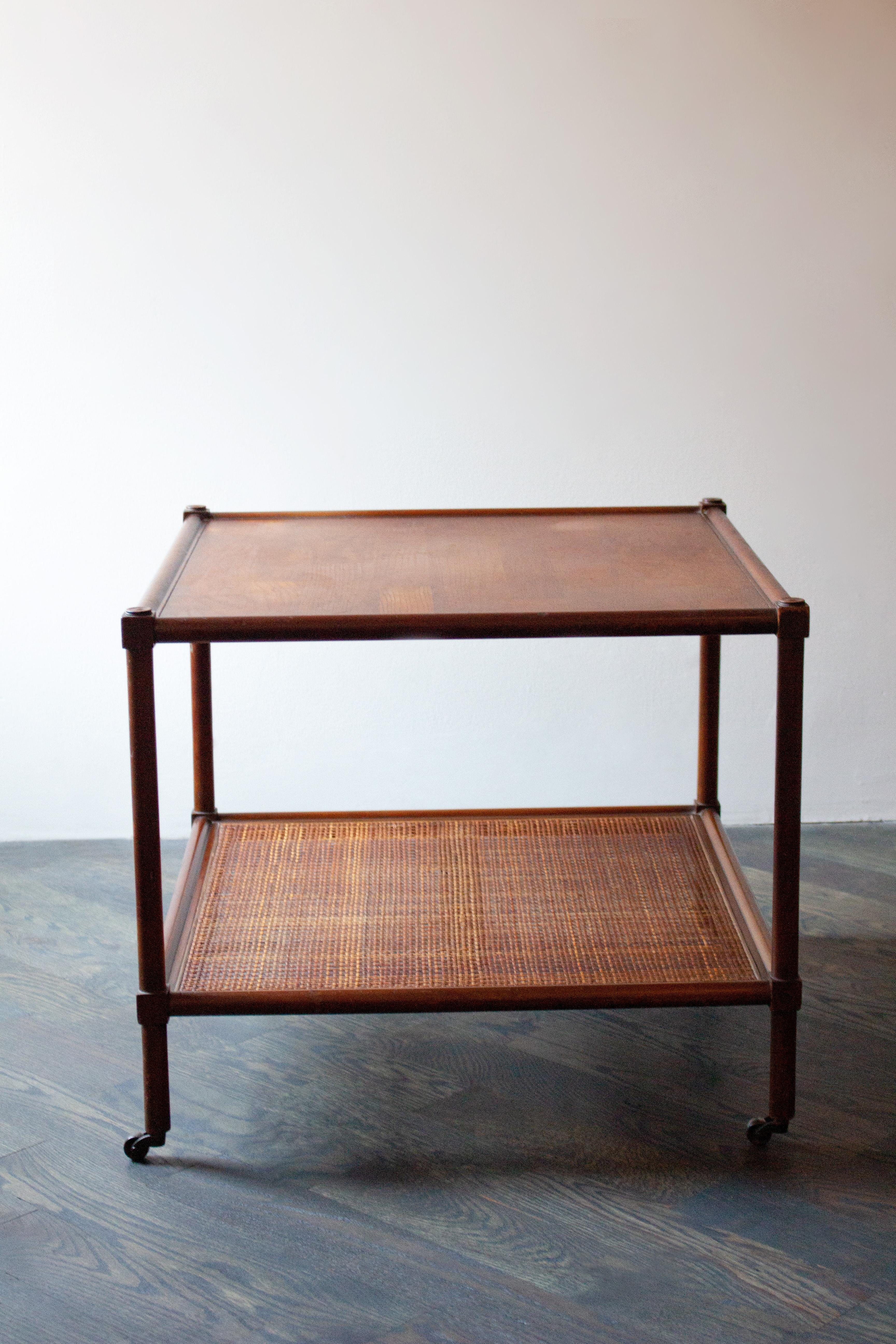 Beautiful and simplistic rolling rattan and wood table. The bottom shelf allows for extra storage and versatility on this lightweight, square table. 

Please note there is a half inch hole in the rattan on the bottom shelf; however, the rattan is