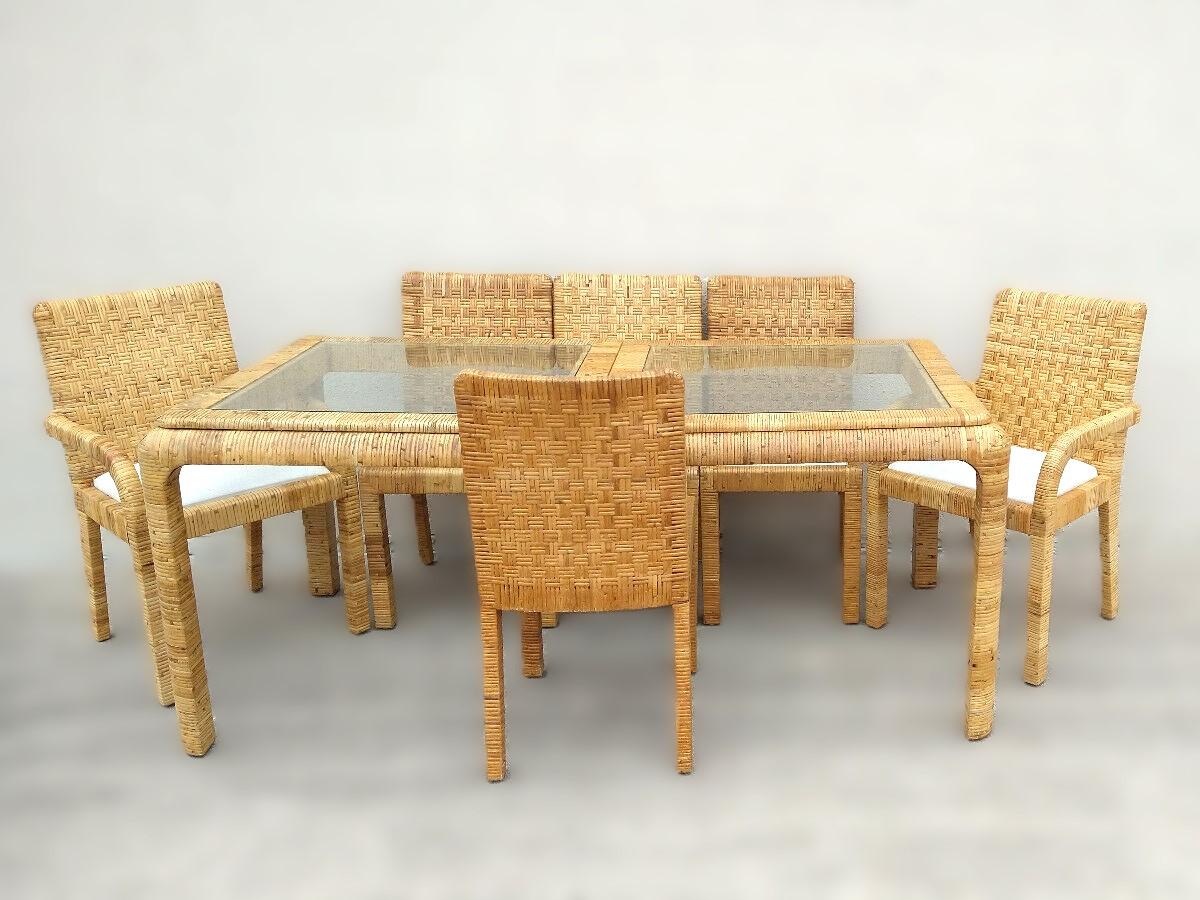 Stunning rattan wrapped waterfall edge dining table with extension leaf. This Billy Baldwin style organic modern dining table is expertly crafted, with a two-panel glass inset top and wrapped rattan over hardwood construction. The rattan wrapped