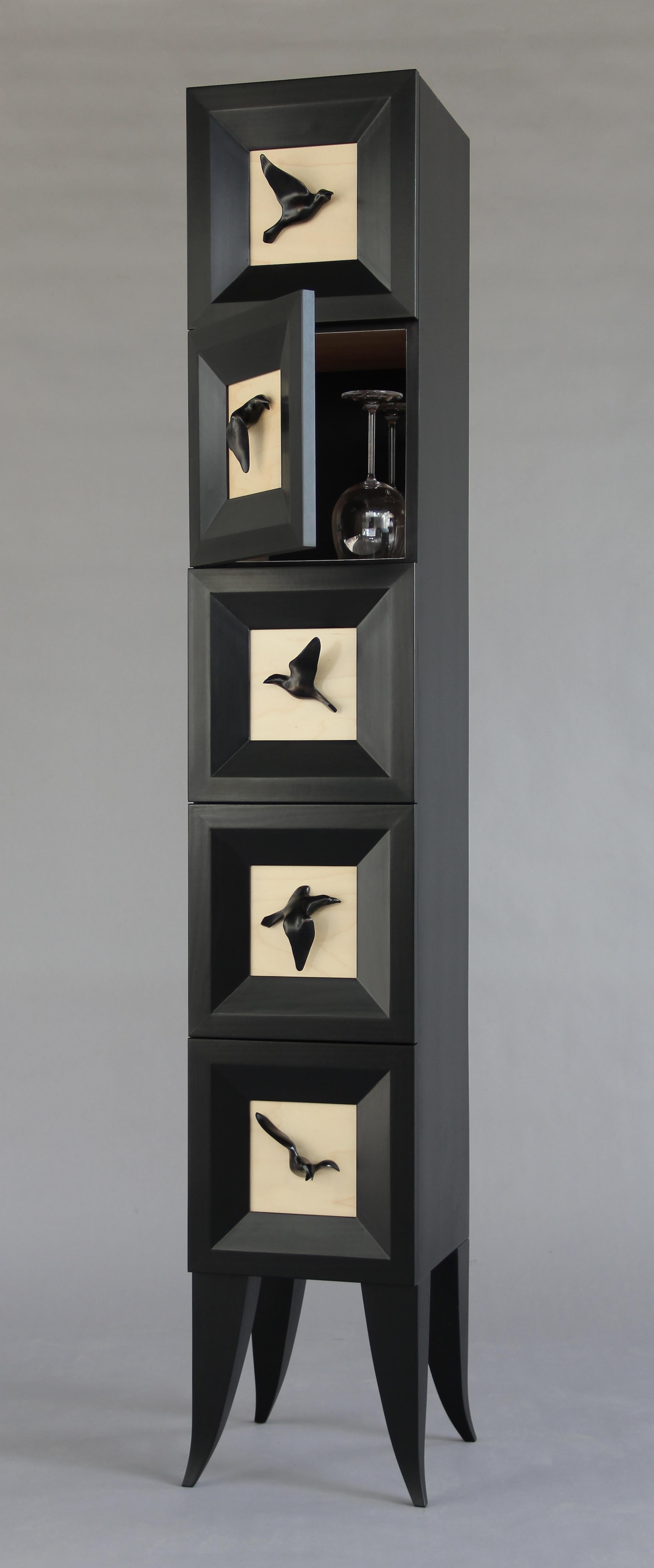 The Raven Tower is a five-door vertical cabinet that is a perfect signature piece for almost any room. It takes up just one square foot of floor space. The door fronts feature cold-cast bronze ravens that are individually carved and cast by the