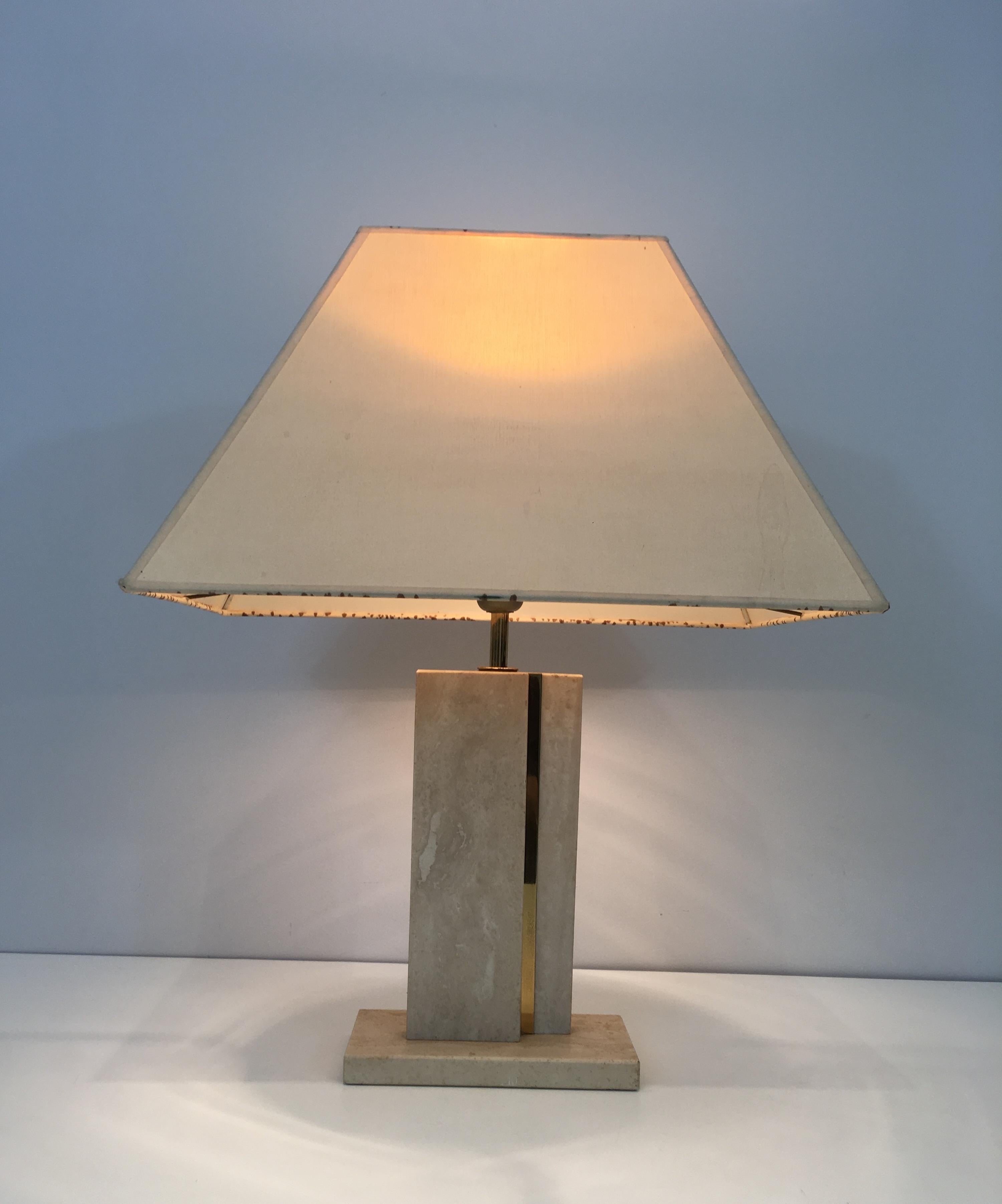 This very nice table lamp is made of travertine with a brass line. This is a nice design and a French work, circa 1970.
