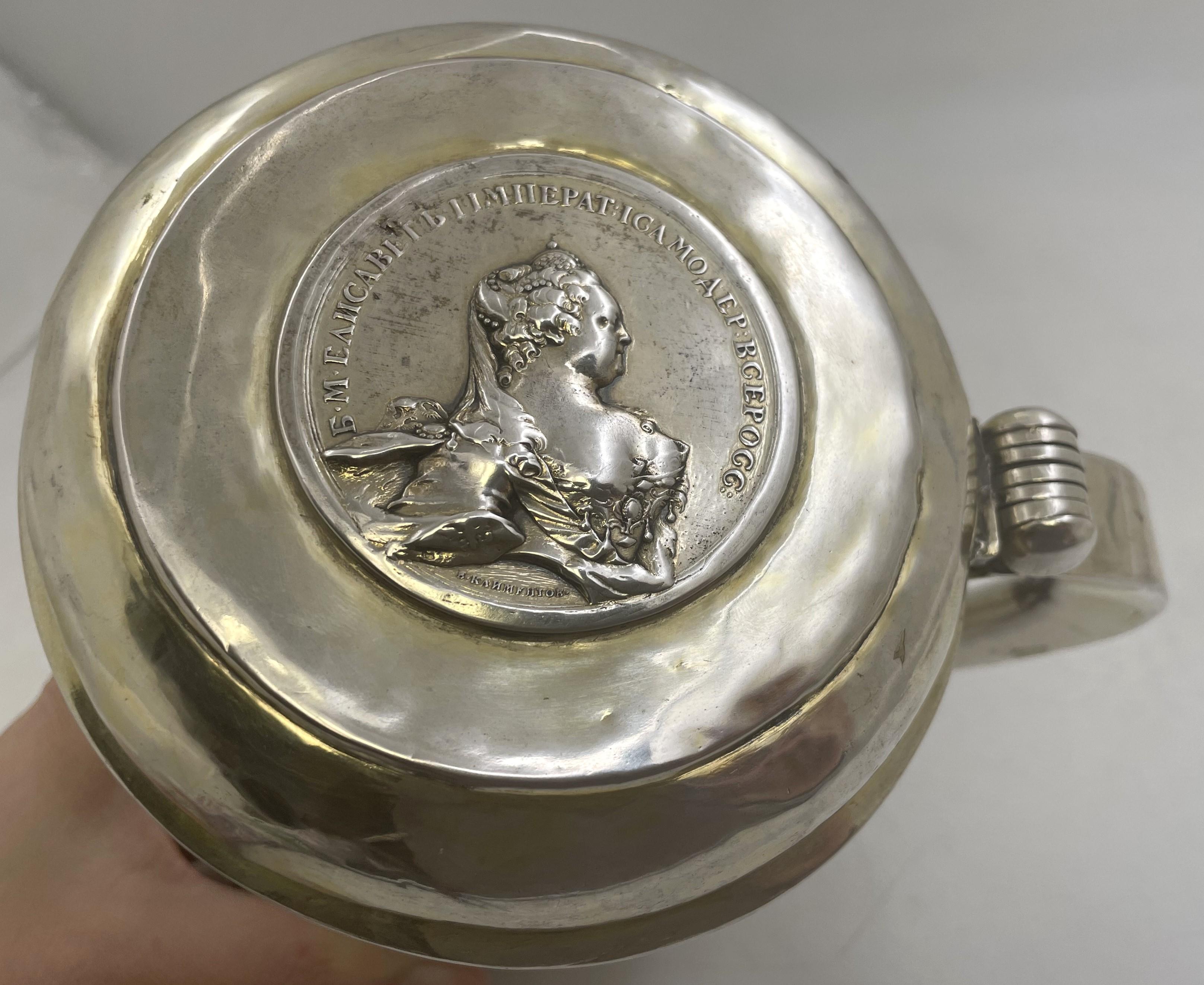 Boccale d'argento russo del XVIII secolo che commemora la morte dell'imperatrice Elisabetta Petorvna (1709-1761) con una moneta a doppia faccia inserita nel coperchio. Probabilmente è di J. Ravich. 

Misura 6 1/4'' (15,9 cm) di altezza per 7'' (17,8
