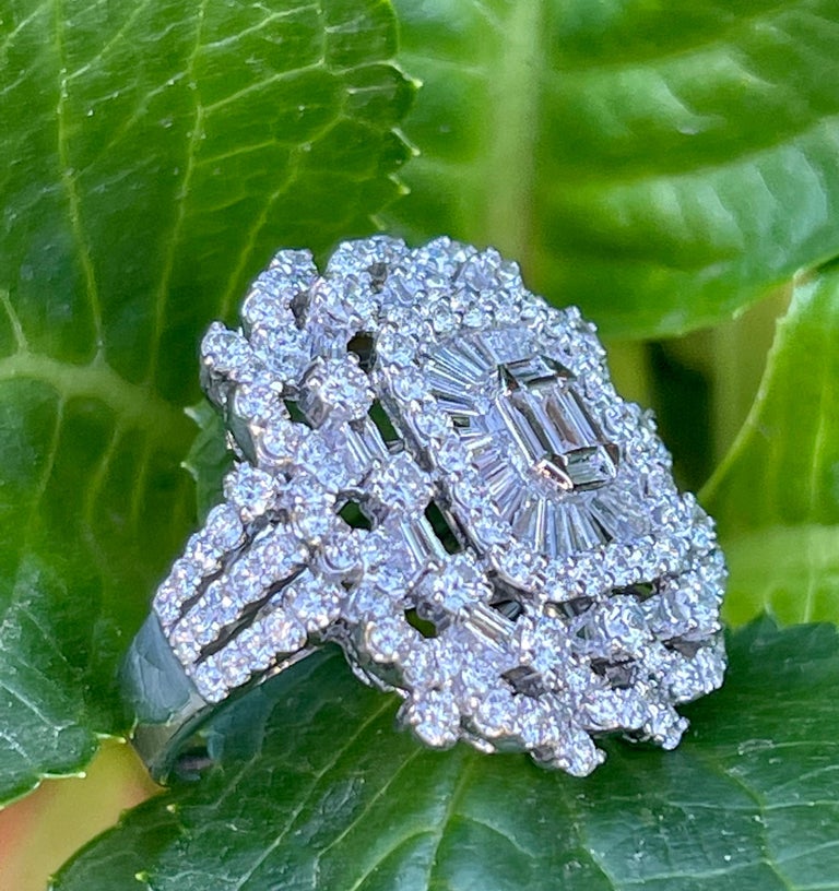 Ravishing 18 karat white gold diamond cocktail ring features a slightly domed rectangular shaped ballerina center with an array of diamonds in the middle creating an illusion of an emerald shaped diamond as the focal point. Surrounding the emerald