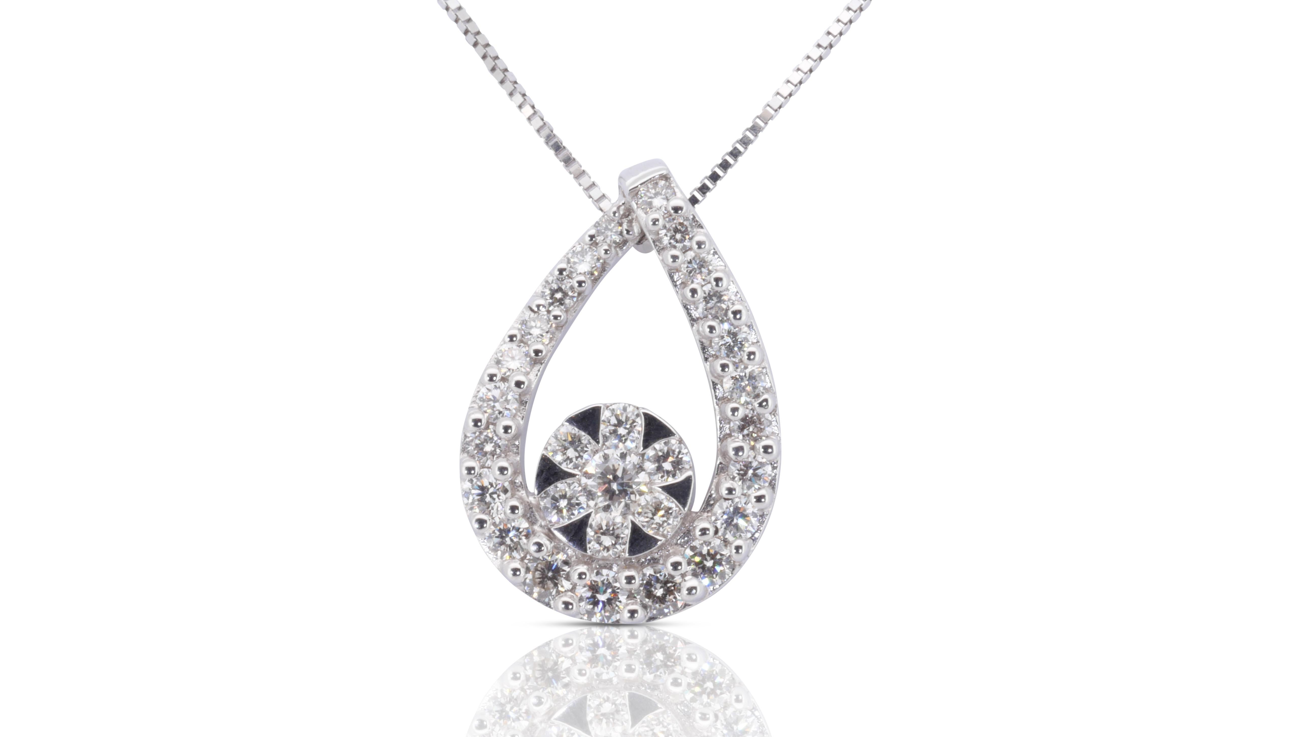 Un magnifique pendentif orné d'un éblouissant diamant naturel de 0,98 carat de forme ronde et brillante. Elle possède 0.05 carat de diamants latéraux qui ajoutent encore à son élégance. Le bijou est fabriqué en or blanc 9 carats avec un polissage de