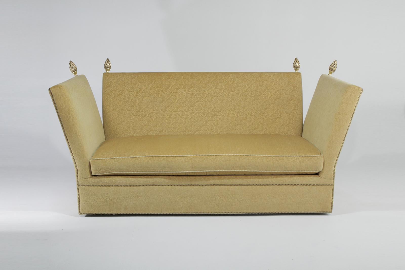 Very glamorous Classic Knole style sofa upholstered in a beautiful soft shade of goldish yellow silk velvet. The sides do not lower but are static. The seat cushion is detachable. Gorgeous brass nailhead detailing and gilded pine cone finials as
