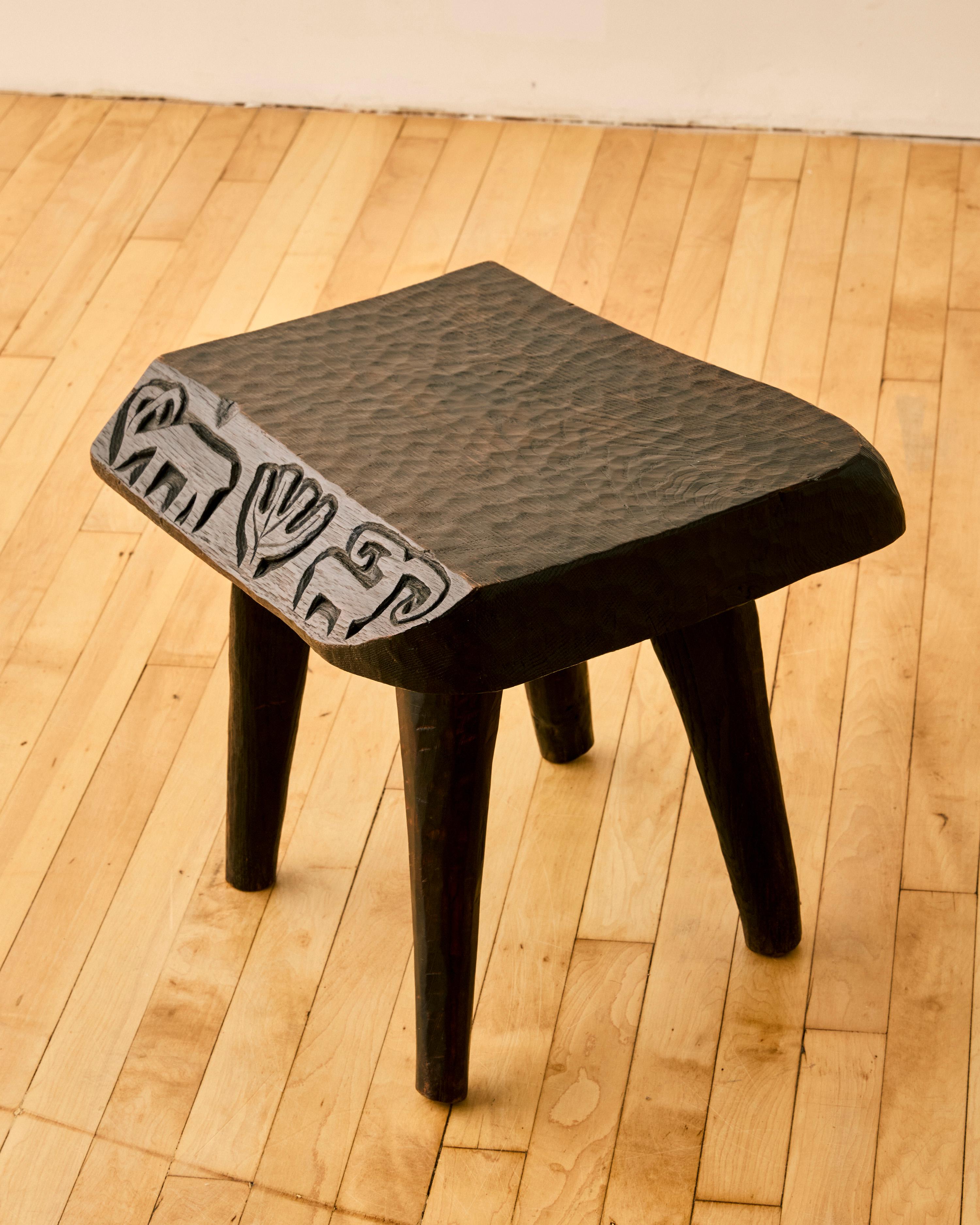 Tabouret en bois foncé à bord brut avec un design sculpté par Willy Trojan. 