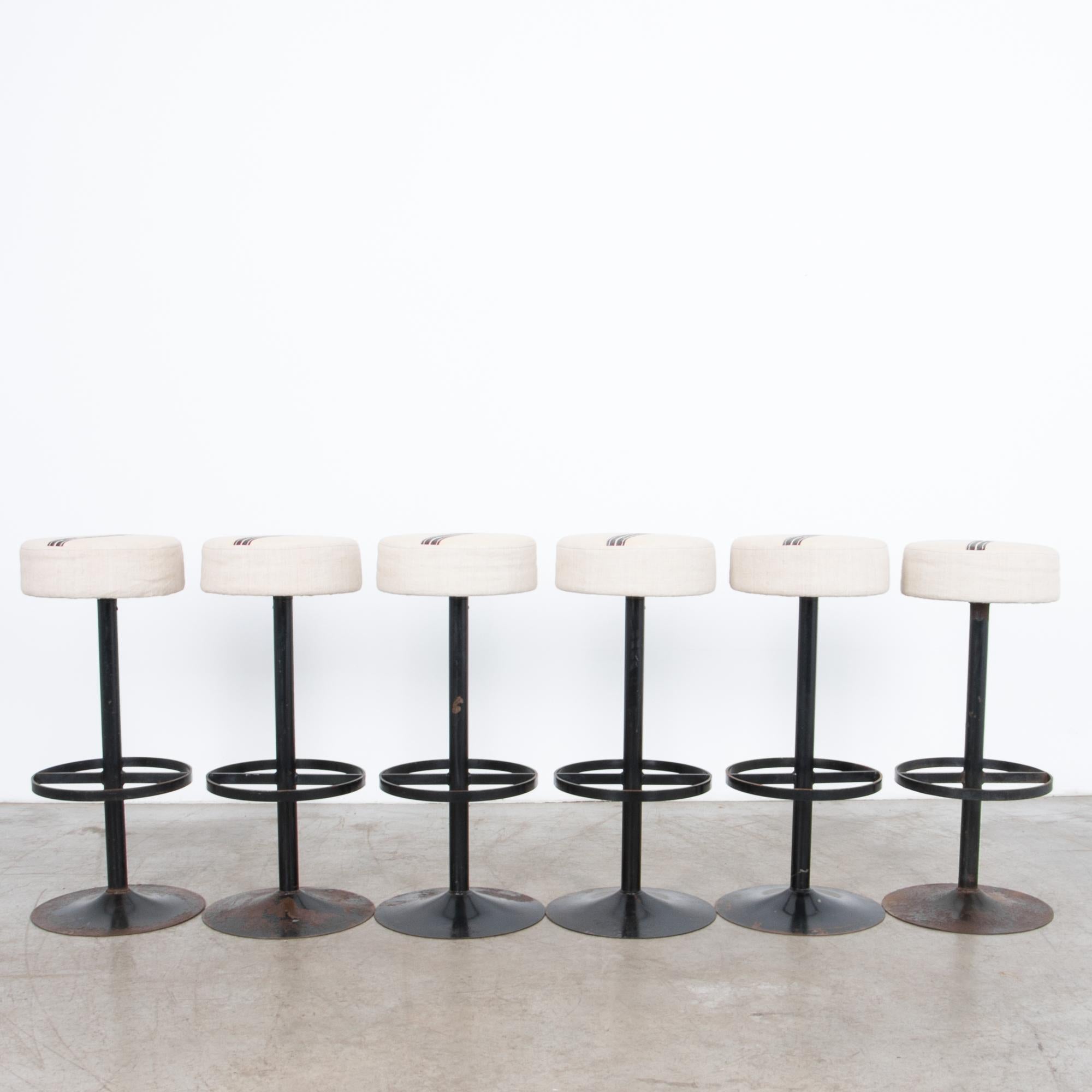 From 1970s Belgium, six sleek steel stools with a minimal designed base topped with a maroon striped fabric seat. Oxidized black enamel, updated and polished with unique upholstered tops cut from vintage patterned linen.