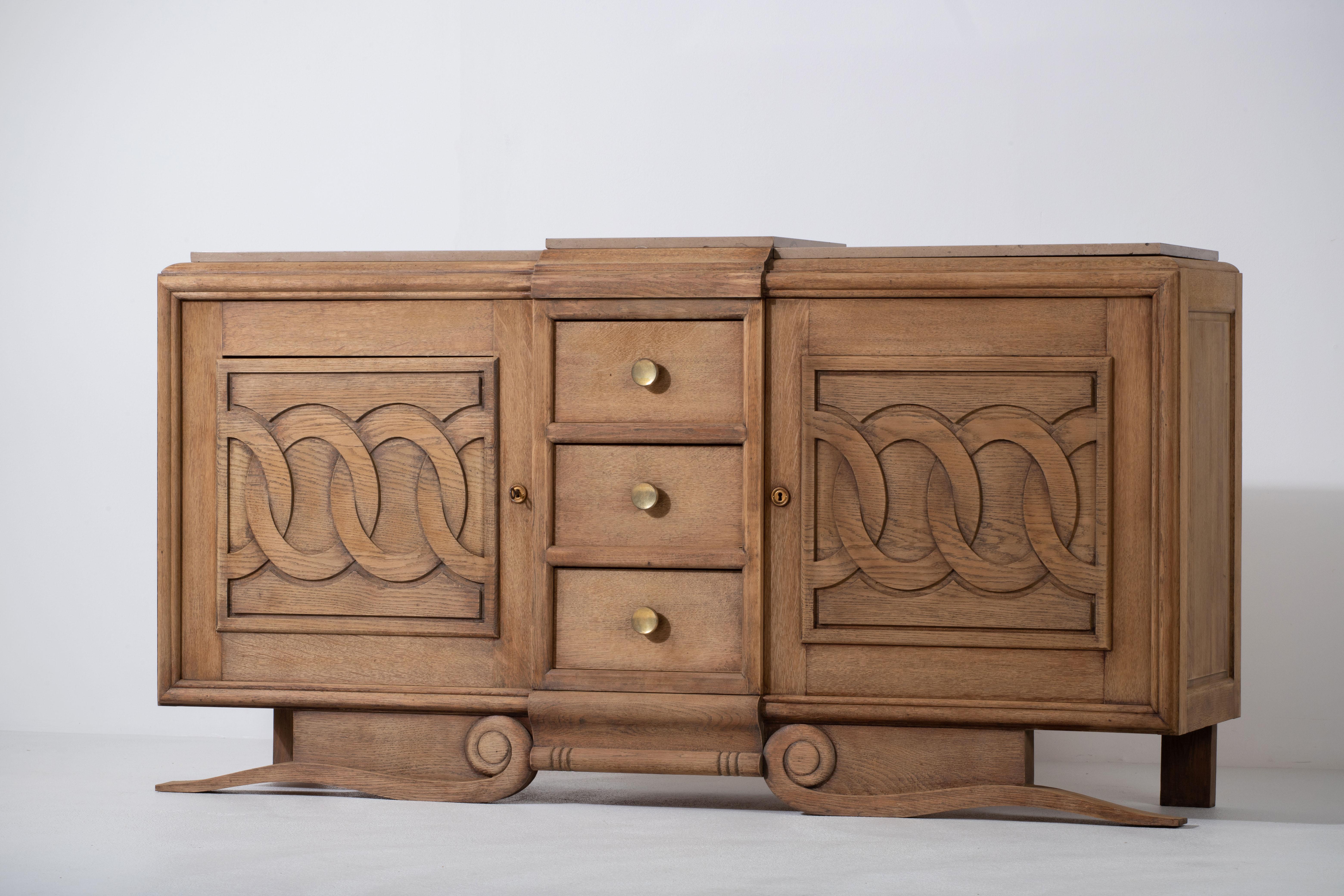 Credenza, solid oak, France, 1940s.
Art Deco brutalist sideboard. 
The credenza consists of two storage facilities and covered with very detailed designed doors and in the center, a drawers column.