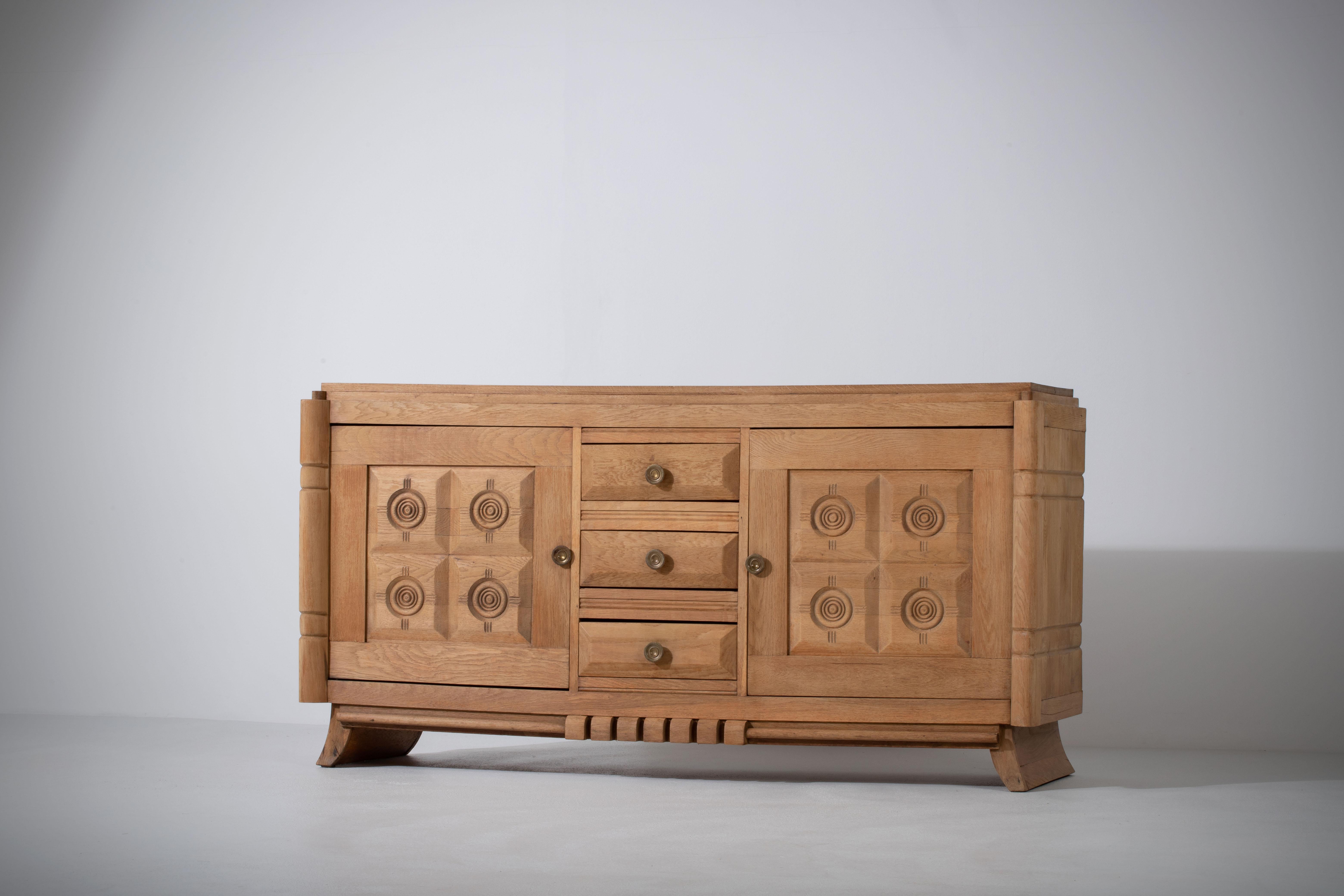 Credenza, solid oak, France, 1940s.
Art Deco Brutalist sideboard. 
The credenza consists of two storage facilities and covered with very detailed designed doors and in the center, a drawers column.