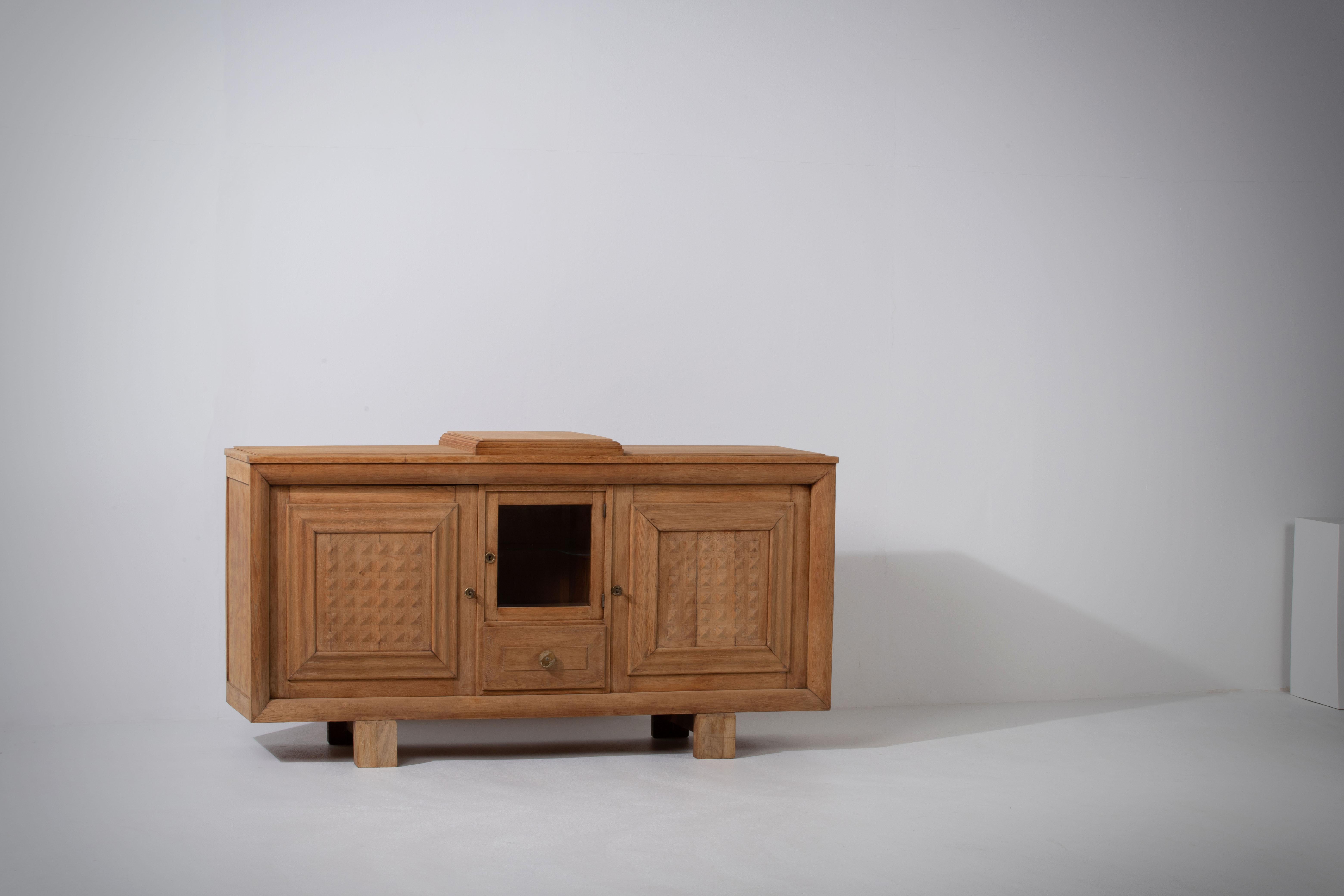 Introducing an extraordinary Art Deco Brutalist credenza from France, crafted in the 1940s. This remarkable piece showcases a solid oak construction, exuding both strength and elegance.

The credenza features two storage compartments, offering