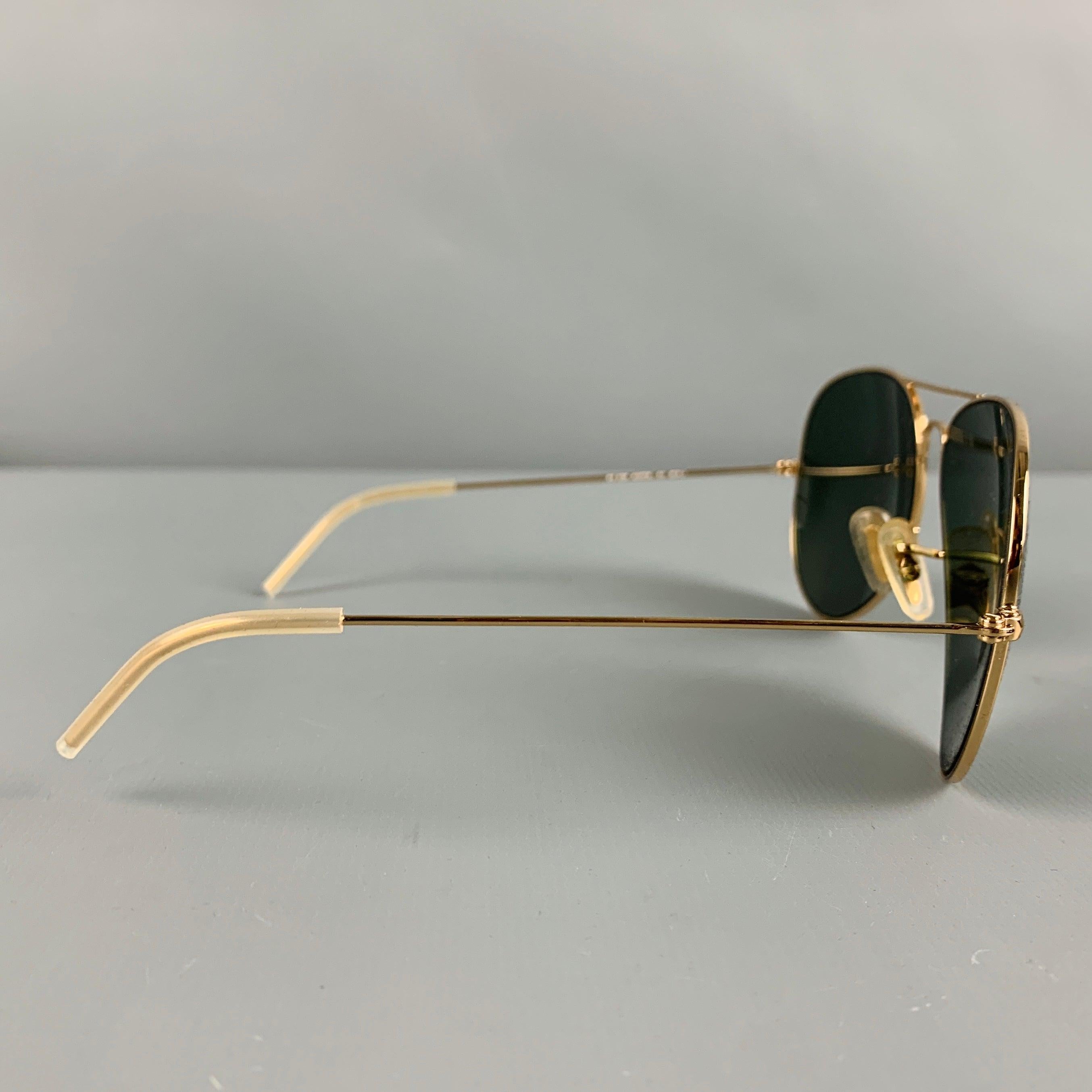 RAY-BAN sunglasses in a gold tone metal featuring an aviator style, and tinted lenses. Comes with case. Made in Italy.Very Good Pre-Owned Condition. Minor signs of wear. 

Marked:   RB 3025 AVIATOR L 001 62 14 

Measurements: 
  Frame Width: 15.5