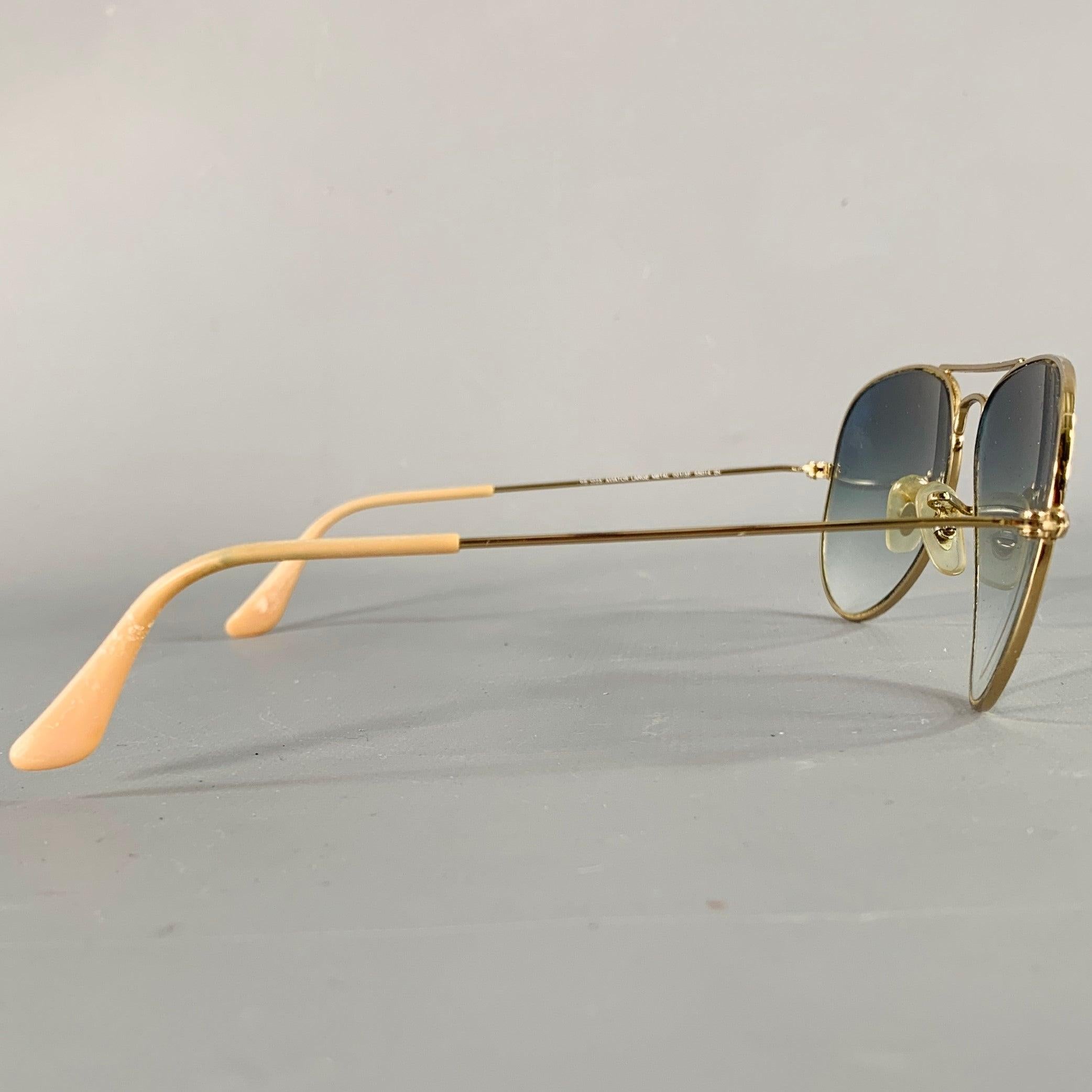 RAY-BAN sunglasses
in a gold tone metal featuring an aviator style and tinted lenses. Comes with case.Very Good Pre-Owned Condition. Tears on back of case. 

Marked:   RB 3025 

Measurements: 
  Frame Width: 13 cm.Frame Height: 4 cm.
  
  
 
Sui