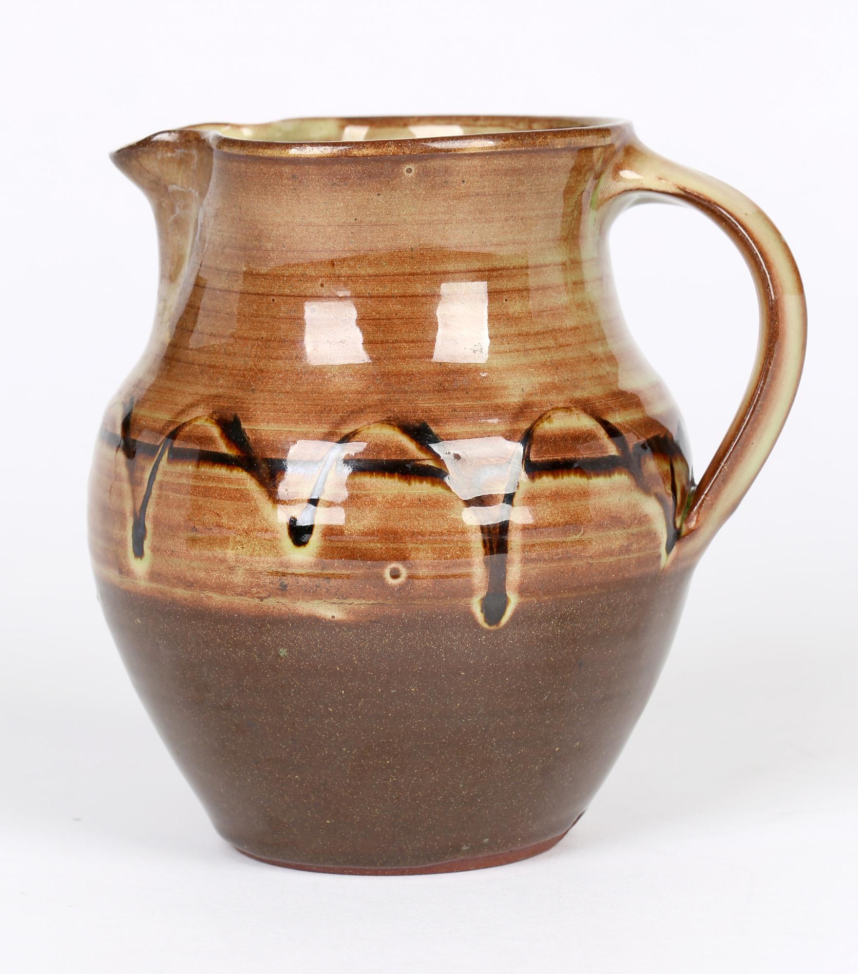 A very finely made vintage Winchcombe studio pottery handled jug with trailed slipware patterning attributed to Ray Finch and probably dating from the 1950's. This well potted jug is of rounded bulbous shape with an unglazed terracotta colored clay