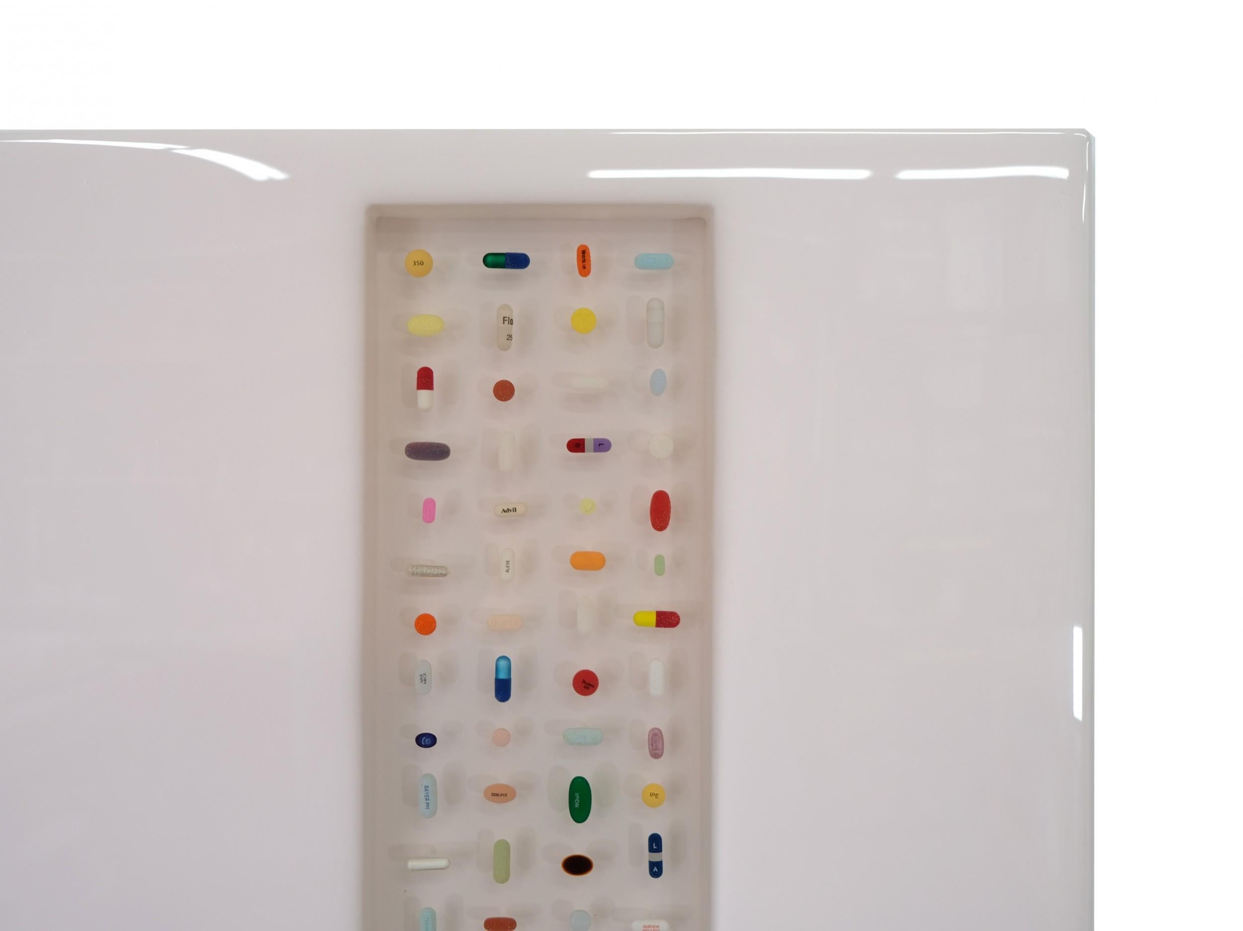 Contemporary abstract resin sculpture comprised of a rectangular white resin slab with a translucent off-center rectangular window in which various colorful pills are suspended. (RAY GEARY)

Condition: Good; Wear consistent with age and use