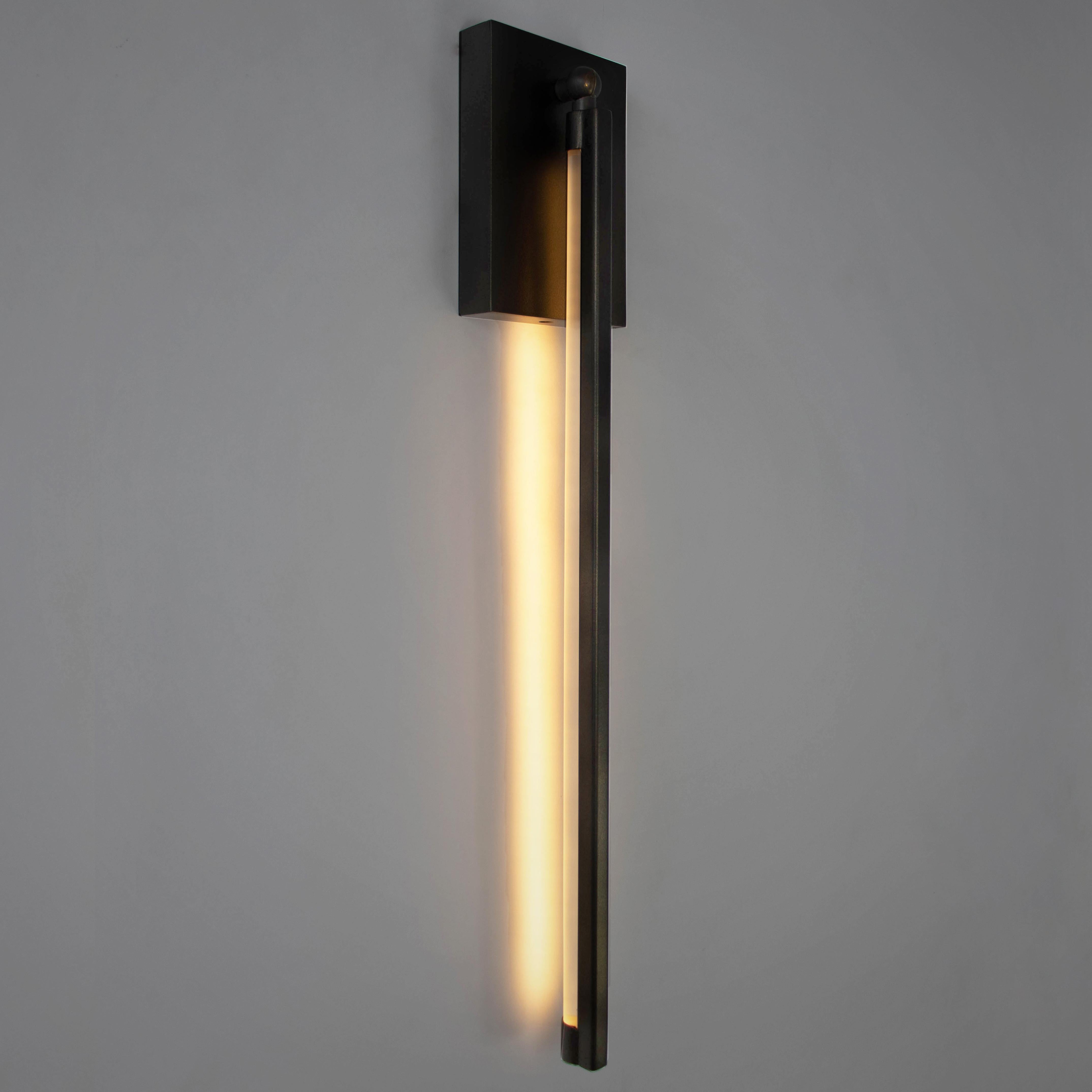 The RAY slim wall sconce is built from cold-rolled steel, and is diffused by a minimal frosted, round acrylic rod. The fixture is back-lit with warm white LED strip. The diffuser for this wall sconce can be positioned inward or outward facing by