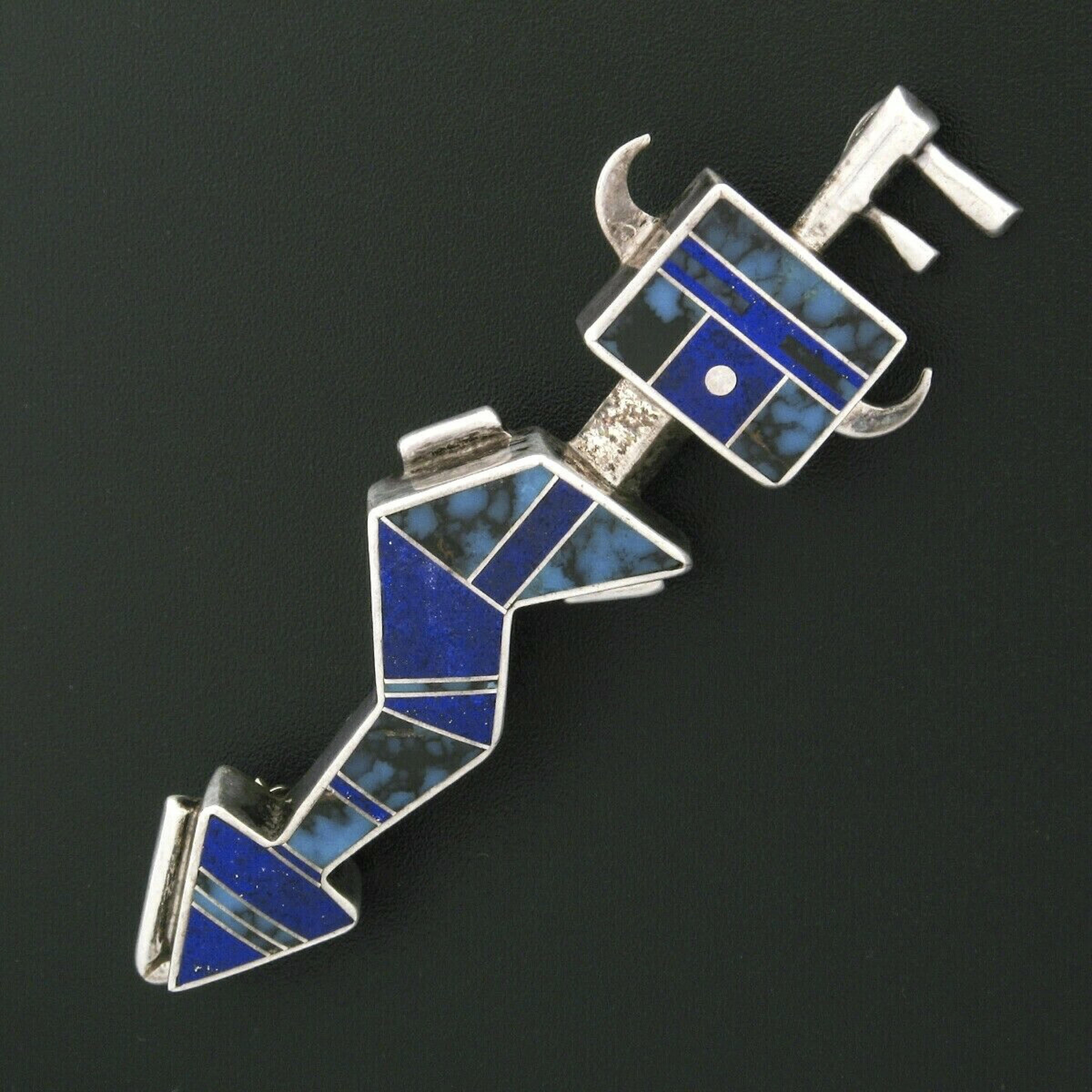This unique hand made Navajo brooch or pendant was crafted from solid 925 sterling silver by Ray Tracey and Knifewing Segura. It features a broken arrow design that is perfectly inlaid with numerous natural lapis and turquoise stones. This piece can