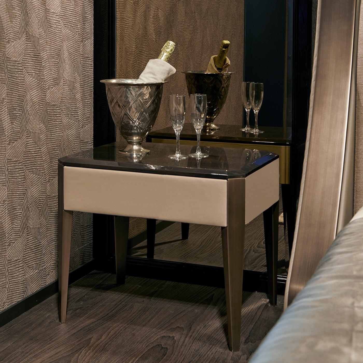 An exquisite design of clean architectural value, this bedside table flaunts an innovative combination of finishes and materials. With a structure made of poplar plywood upholstered of leather or synthetic leather upon choice, it features a