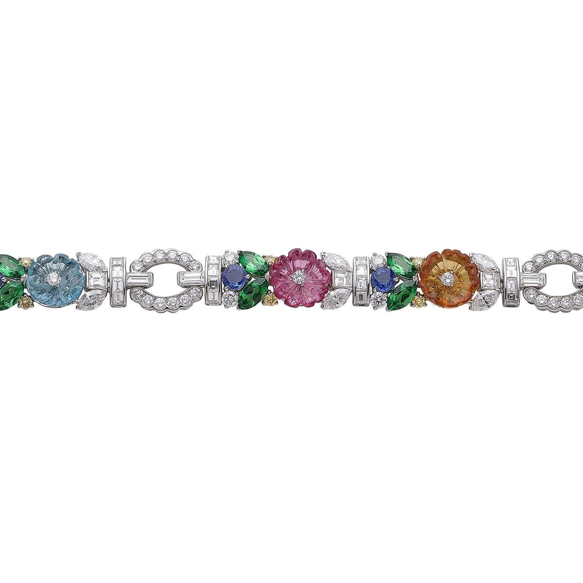 Carved multicolored gemstone flower bracelet with diamond, sapphire, and tsavorite garnet accents, mounted in polished platinum.

Designed by Raymond C. Yard
Six semi-precious carved gemstones weighing 6.57 total carats (aquamarine, rubellite and