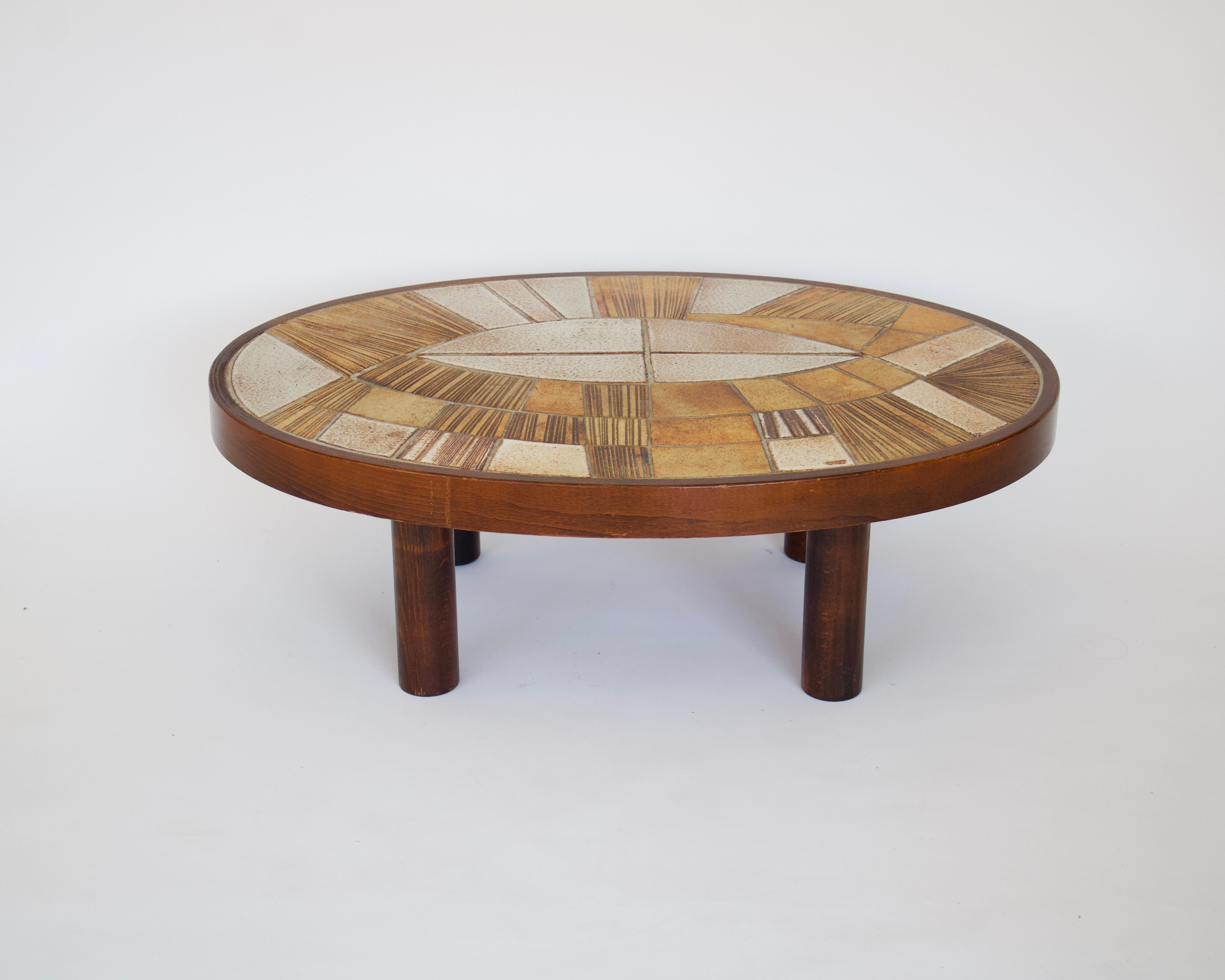 Raymond le Duc French ceramic coffee table in warm tones of browns and honey colored ceramic tiles. 
Oval table framed in mahogany with nice substantial legs. 
The tiles form an abstract drawing and have a lot of texture. 
The artist worked in
