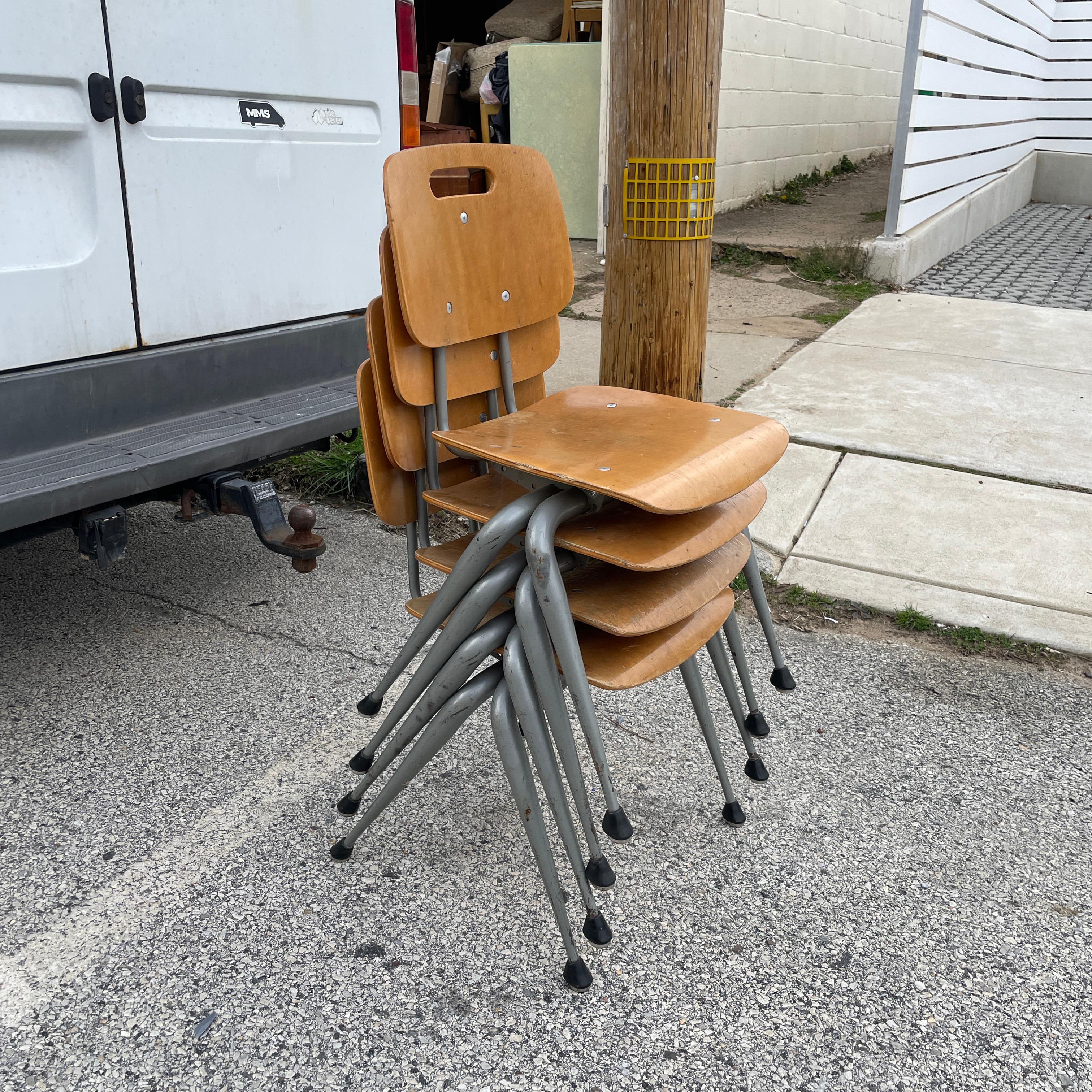 A set of four metal and wood side chairs designed by Raymond Loewy for Brunswick. The chairs stack conveniently. Wooden components show some wear from age and use, but no major damage beyond scuffs, light scratches, and small veneer chips.

Each