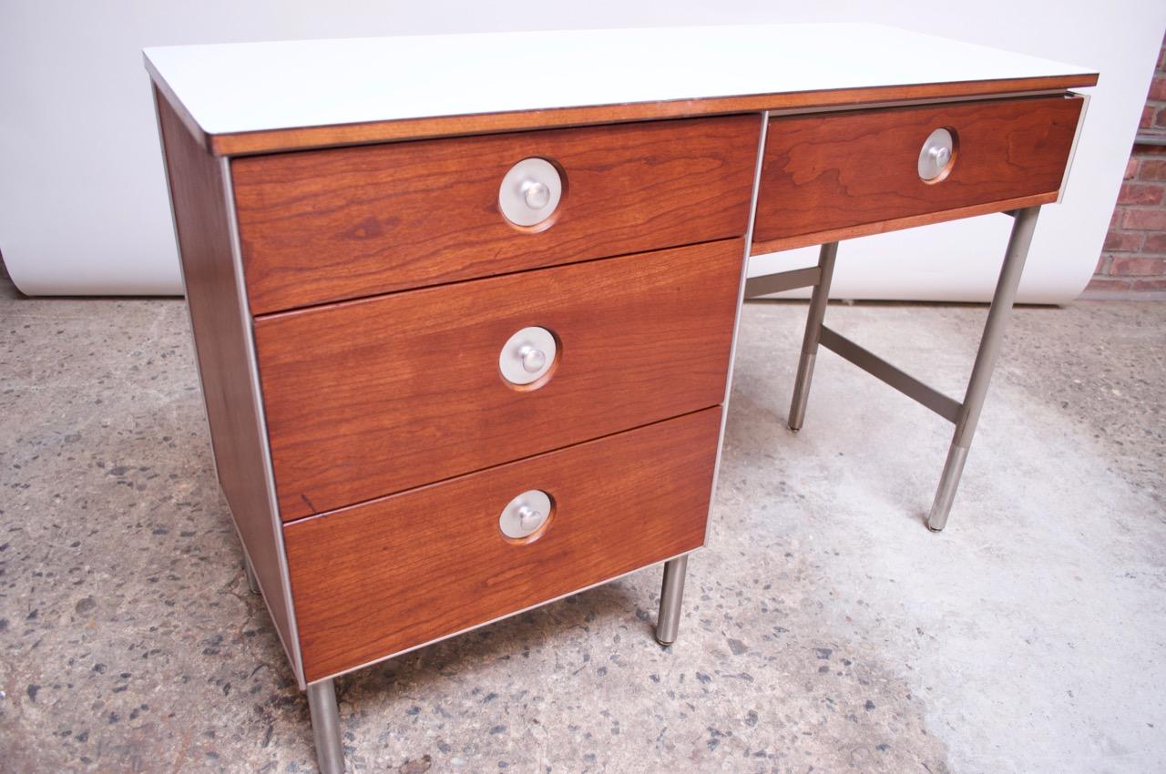 1960s single pedestal desk by Raymond Loewy for Hill-Rom composed of a walnut and brushed metal frame with inset brushed aluminum pulls and laminate top. Restored condition but wear remains (some scratches / scuffs to walnut, one significant gash to