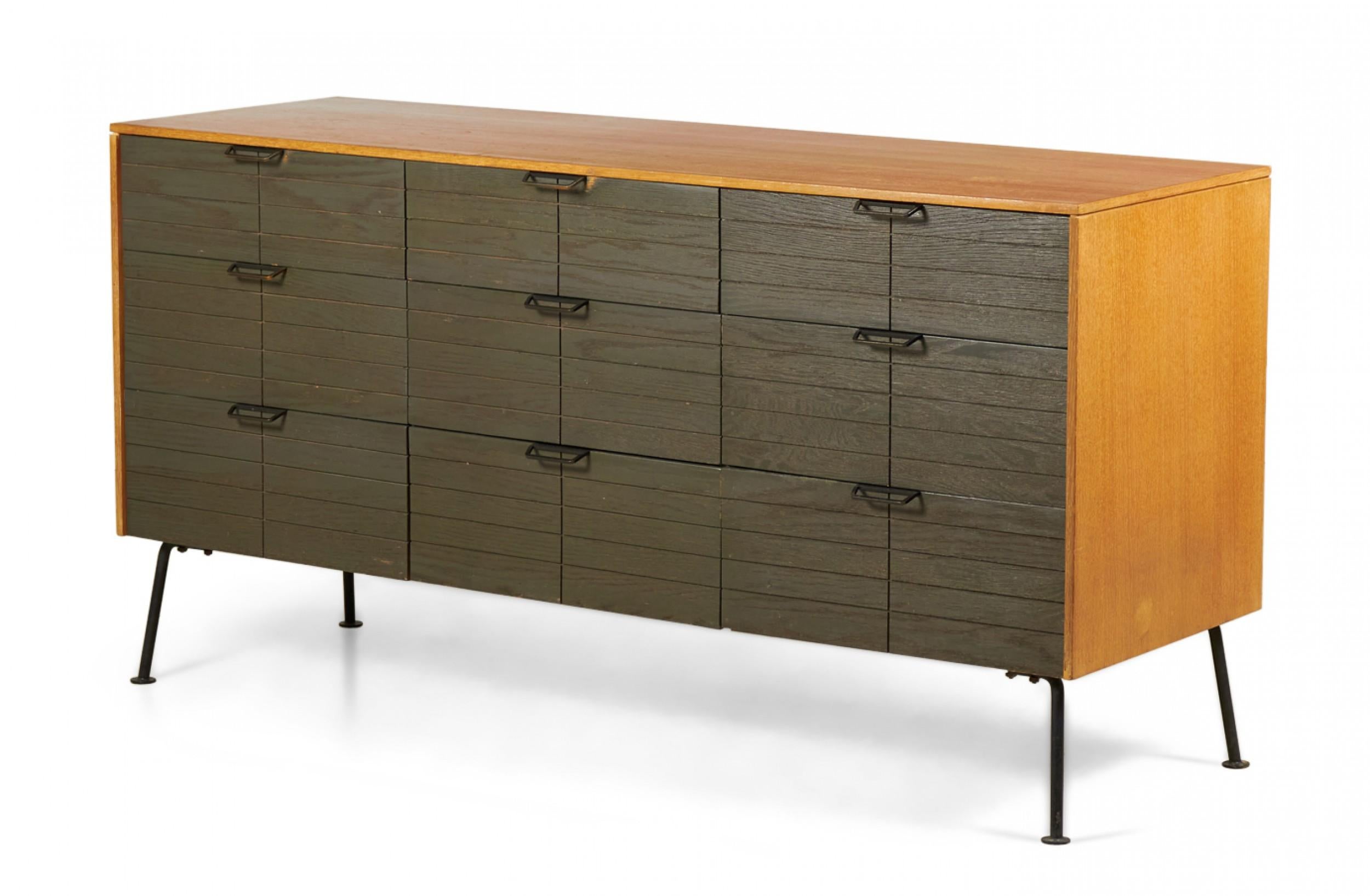 2 American Mid-Century (1950s) 9-drawer dressers with dark brown stained and geometrically incised drawer fronts with trapezoidal iron drawer pulls in a light walnut case resting on four angled iron legs ending in circular feet. (RAYMOND LOEWY FOR