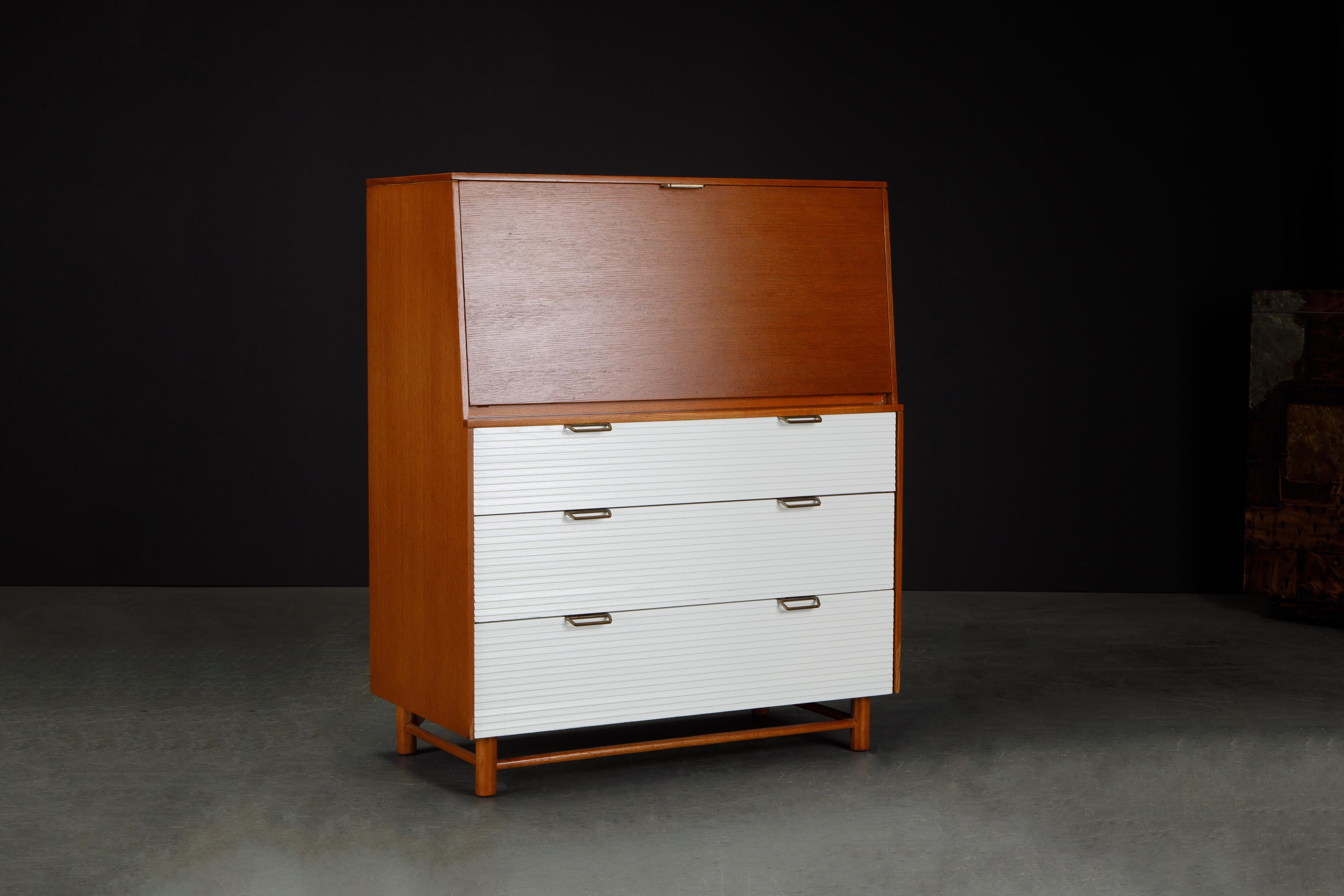 A desirable and rare fully restored highboy secretary dresser by Raymond Loewy for Mengel, circa 1955, comprised of a drop-front secretary with pullout / pull-out storage drawer, cubbies, desktop surface and illuminated with an interior light, and