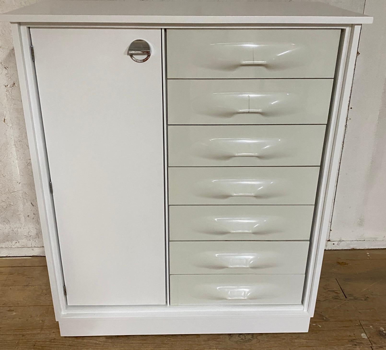 The compact dressing cabinet / tall chest of drawers was designed by Raymond Loewy. The cabinet has a tall door on the left and 7 drawers on the right with characteristic drawer fronts made of white ABS plastic.
   