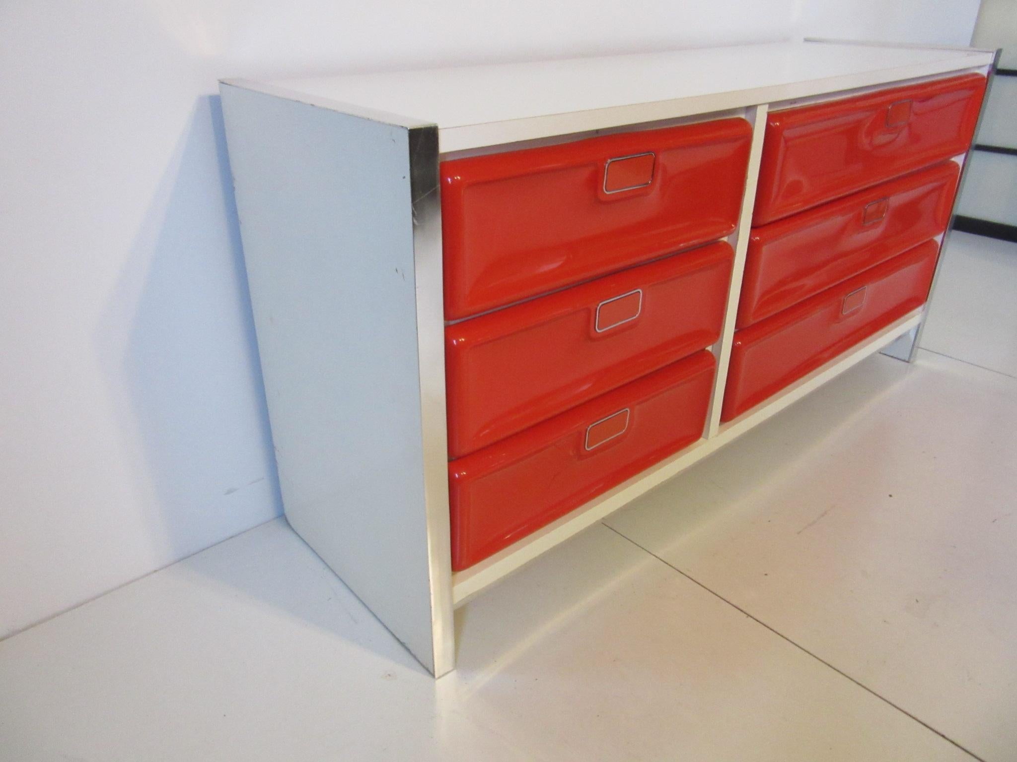A very 1970s six drawer pop dresser with molded plastic fronts , flip metal handles , aluminum edged and white Formica cabinet . In the manner of Raymond Lowey and Broyhill furniture .