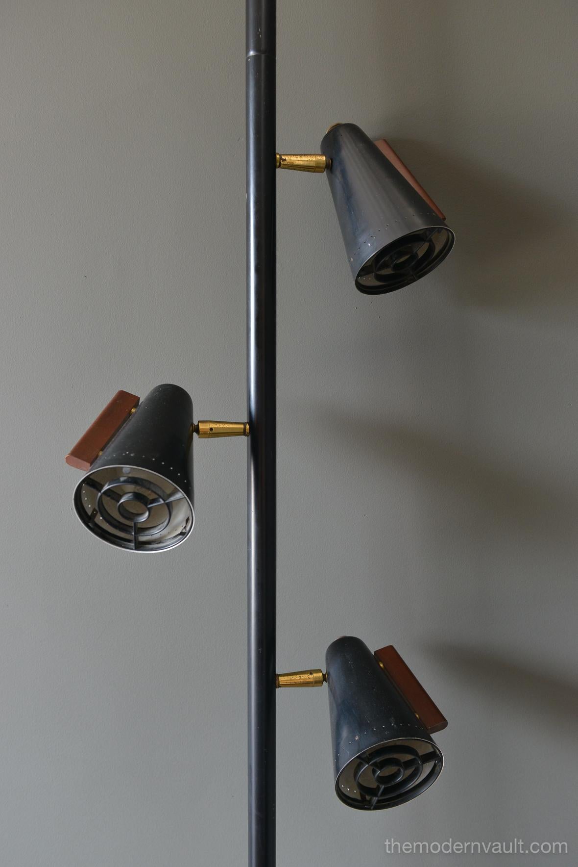 Raymond Lowey for Stiffel tension pole lamp, circa 1965. Black enameled pole and shades with brass and teak accents. Lamp is in good working order, the switch is a 3 way that allows you to turn on each light separately. Retains makers mark on pole,