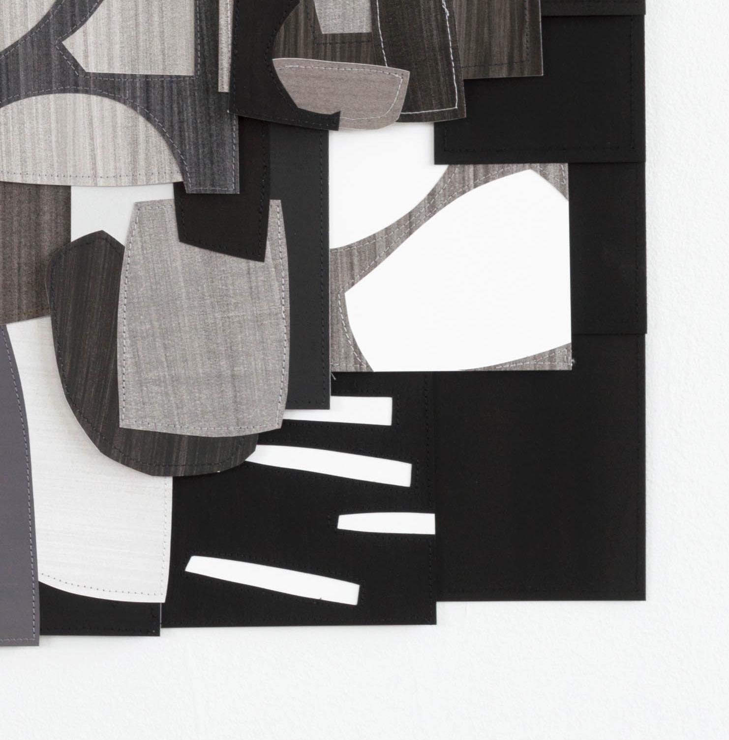 Raymond Saá’s Untitled (F) is primarily black, white, and gray. 

Raymond Saá’s collages are made of hand-painted paper, cut into various shapes that are then sewn together. The end result is an overlapping shingle-like pattern of color, shape, and
